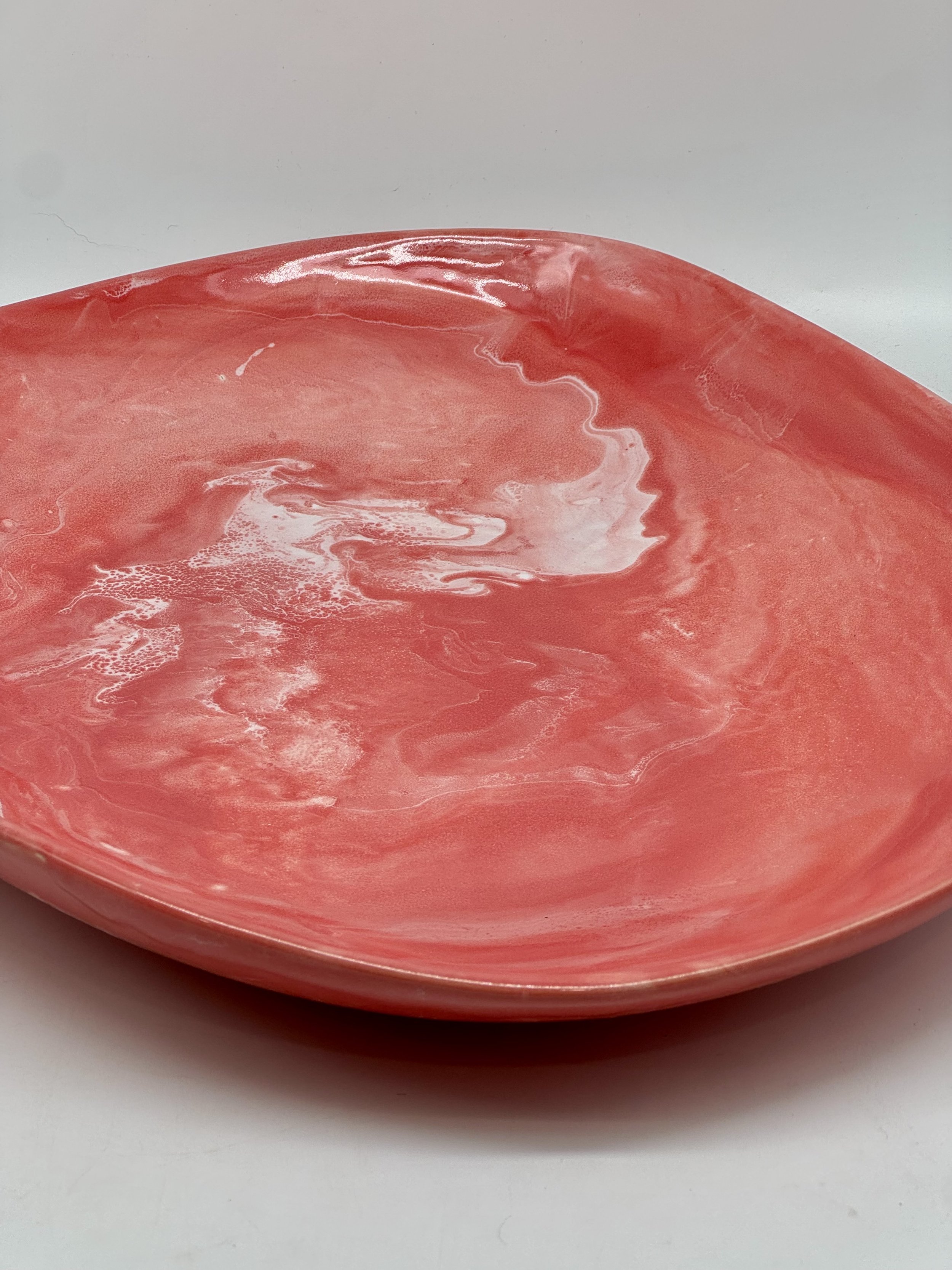 A round ceramic bowl with a pink and white marbled pattern on the inside, placed on a white surface with a light grey background.
