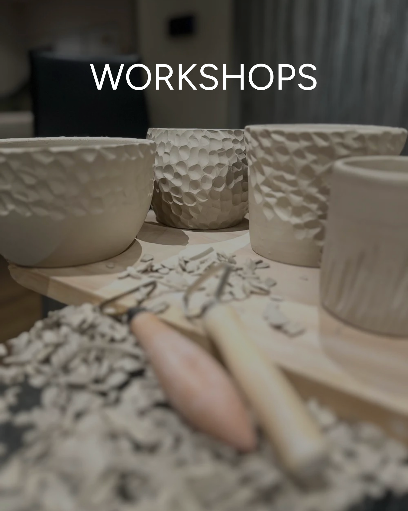 Ceramic bowls with textured surfaces on a wooden table, pottery tools, and clay shavings.