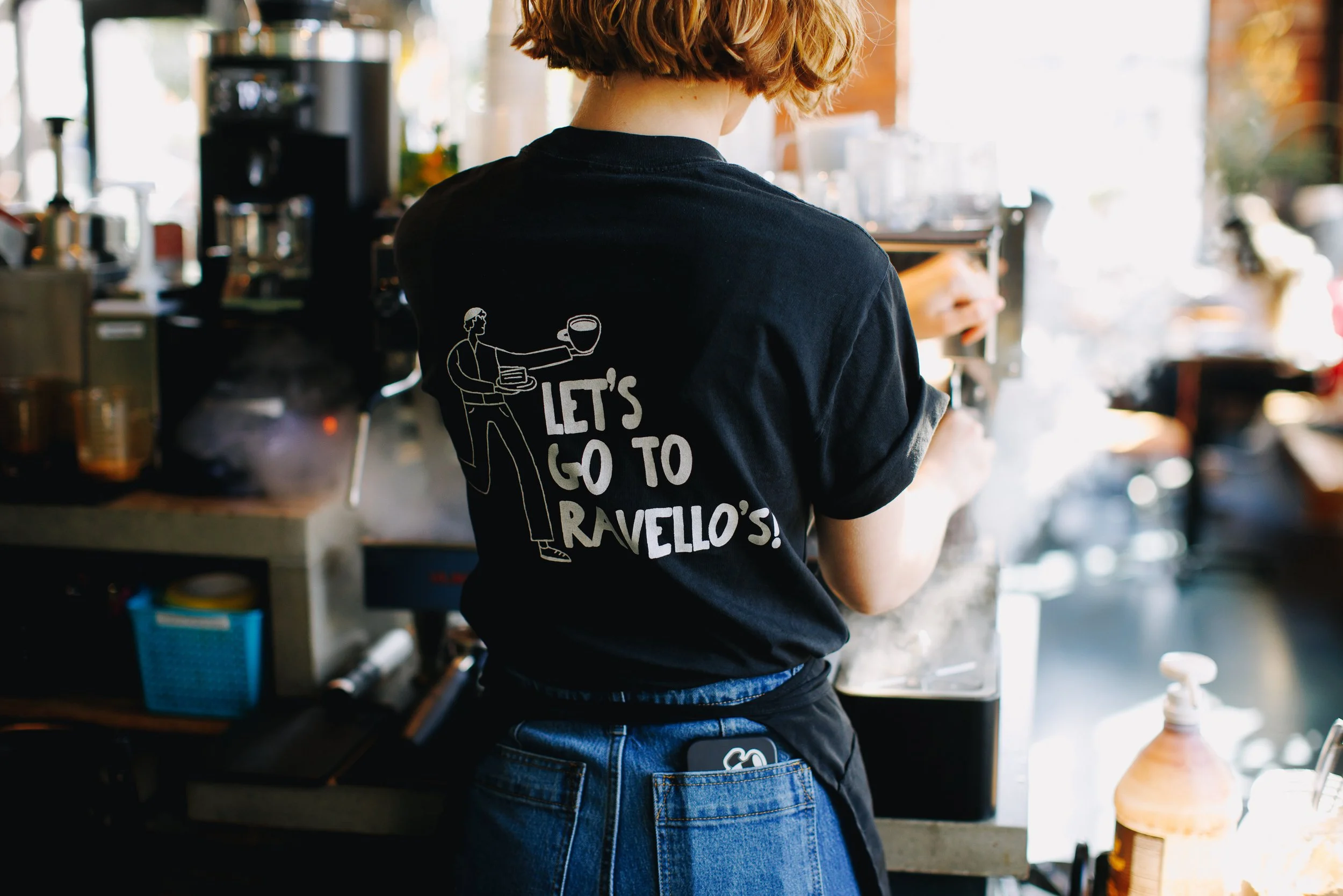Ravello's barista in black shirt making drink behind espresso machine