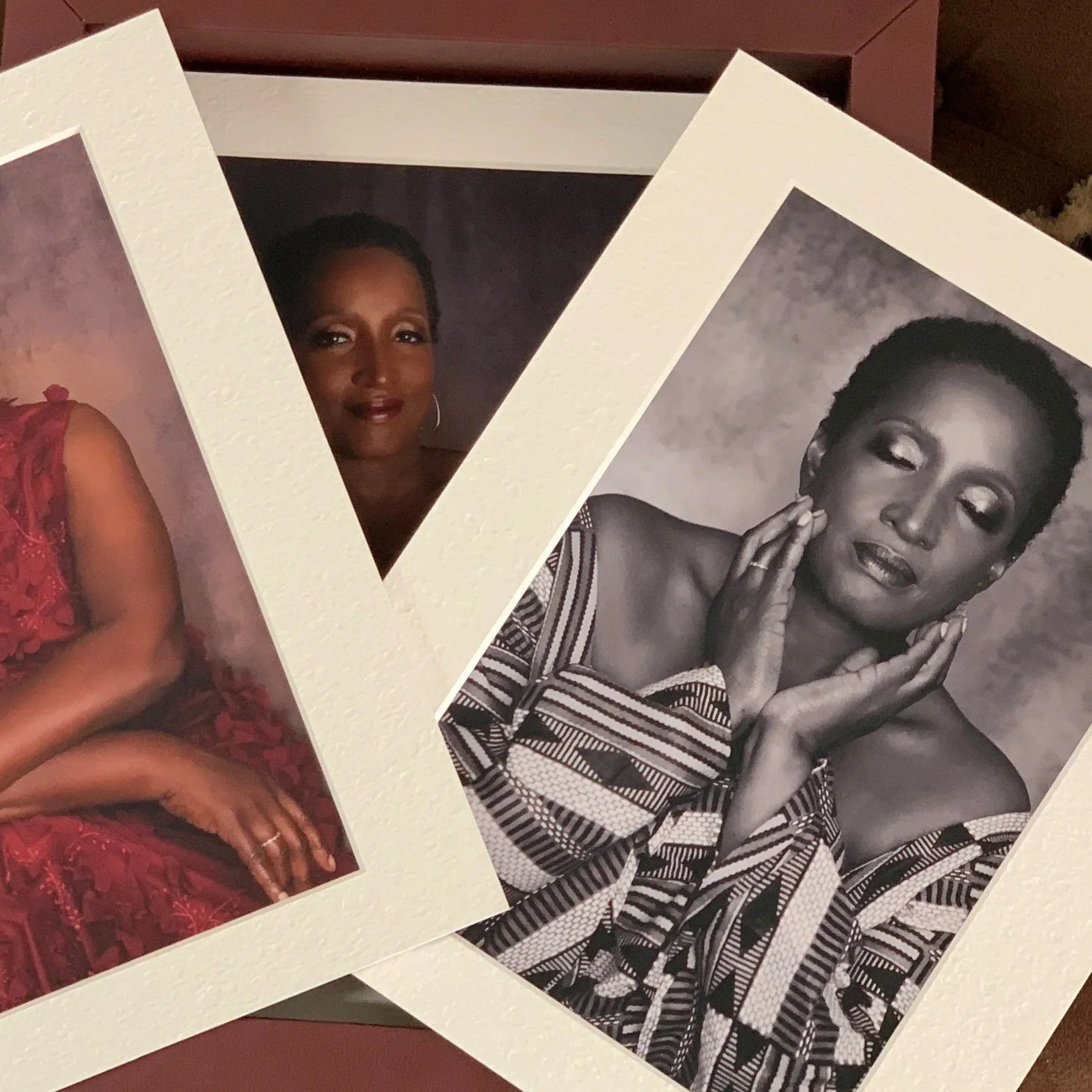Two printed photographs of the same woman, one in color and one in black and white, arranged overlapping on a surface. The woman has short hair and is dressed elegantly.