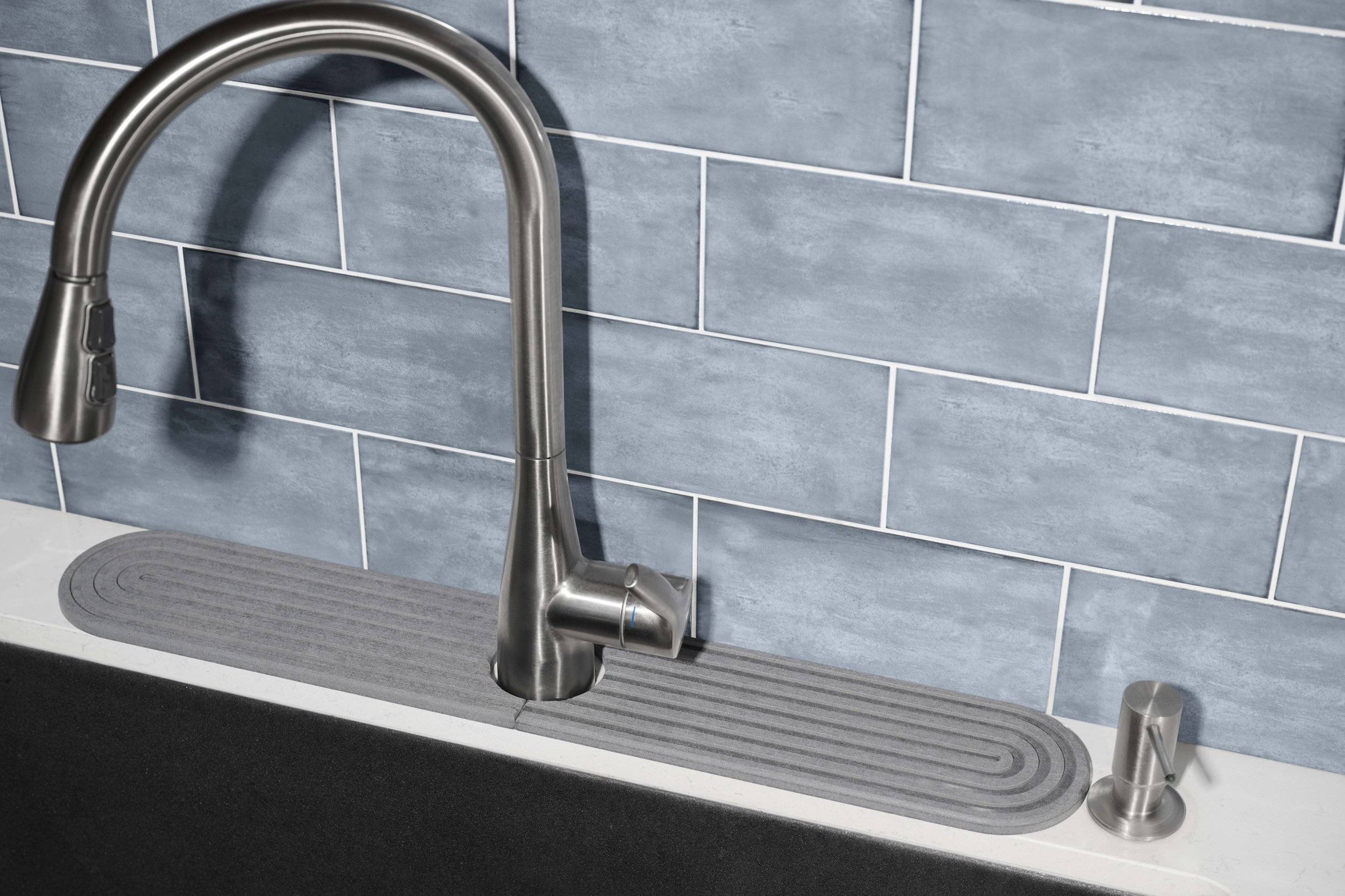 Kitchen sink with a modern stainless steel faucet and a drip tray, set against a blue tiled backsplash.