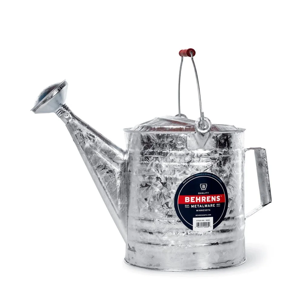 A metal watering can with a sticker that reads Behrens Metalware, Minnesota, with a red and black label, placed against a white background.