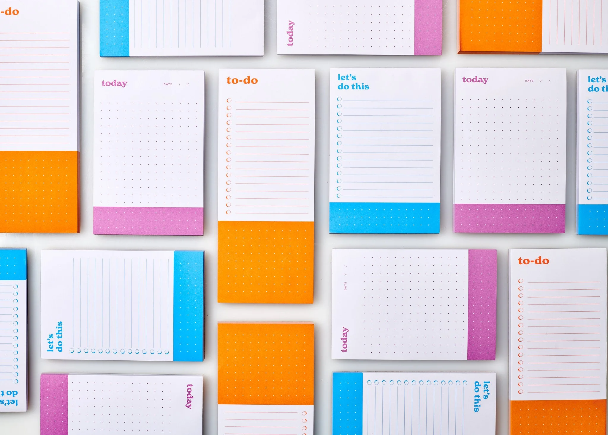 A collection of colorful, patterned notepads and to-do lists arranged on a white surface.