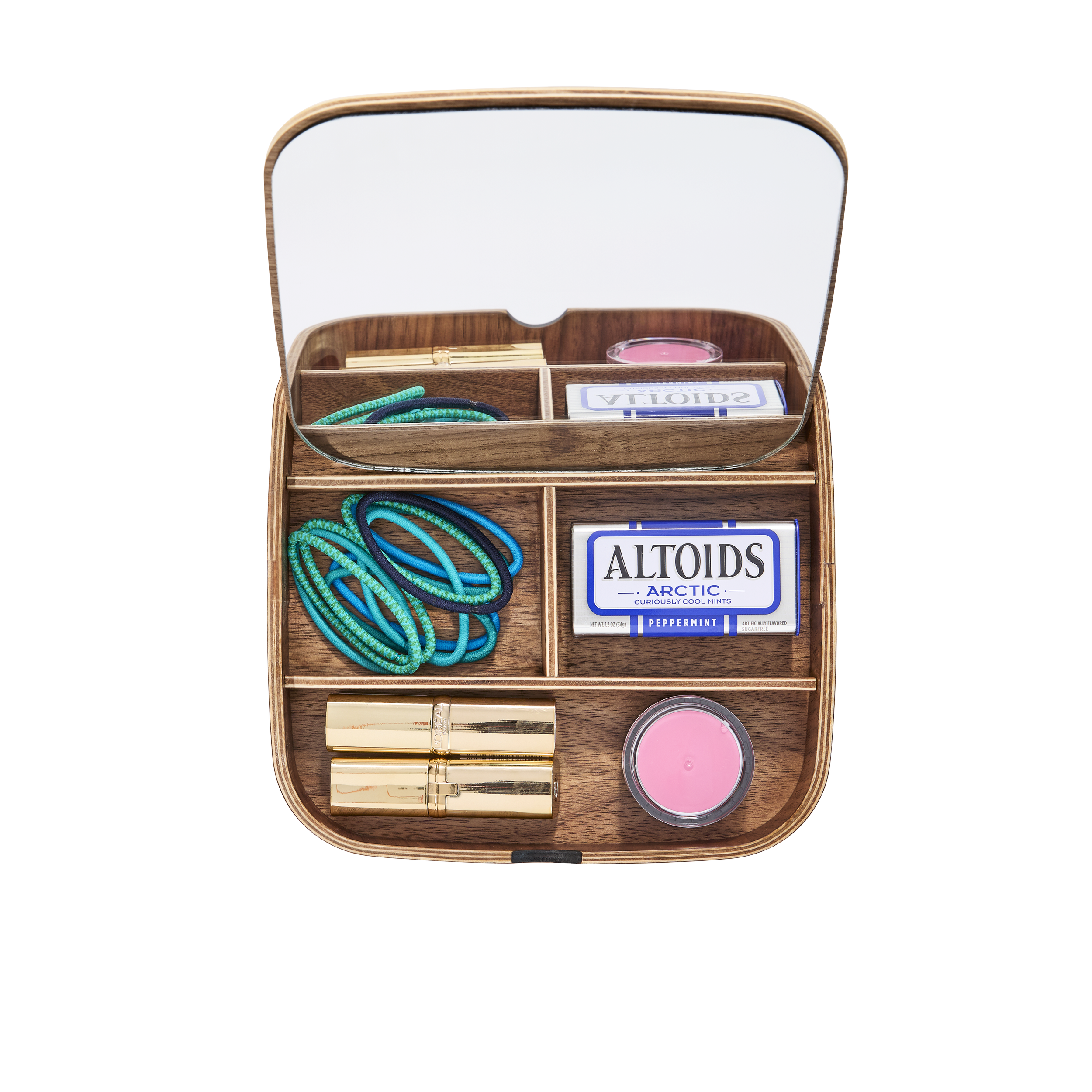 Wooden jewelry box with mirror containing colorful hair ties, a pack of Altoids Arctic mints, a small pink candle, and a gold lipstick.