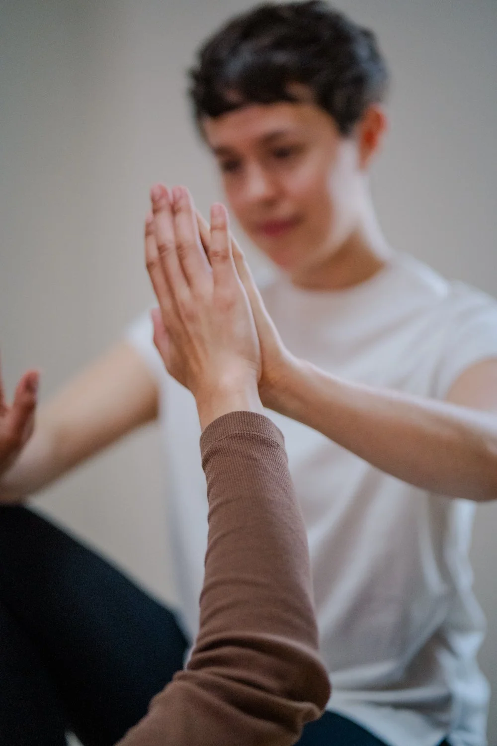 Zwei Personen, die eine Handflächen-zu-Handflächen-Geste, in der Praxis für Körperpsychotherapie von Talea Schütte in Leipzig machen.
