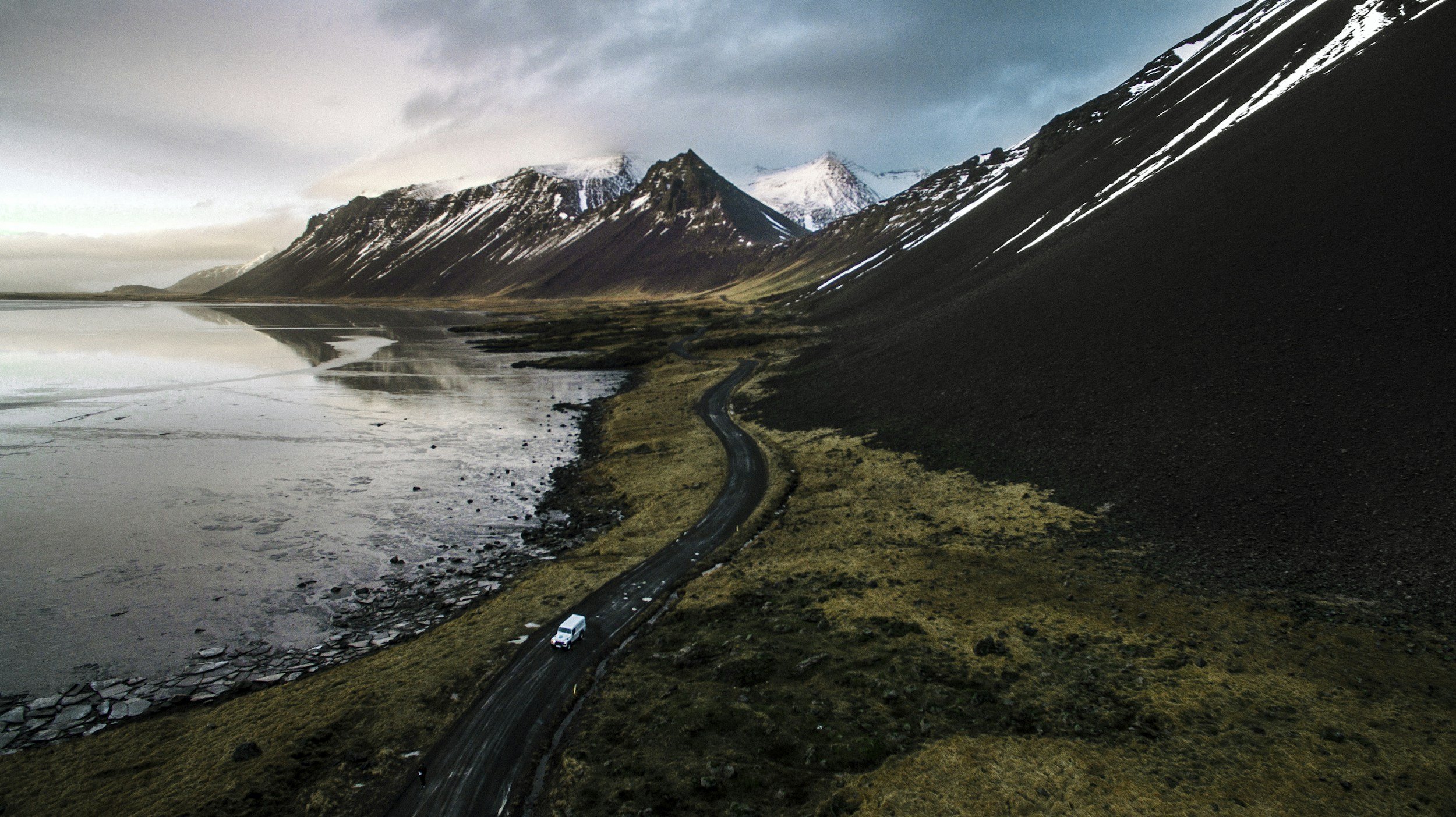 a road through Iceland surrounded by mountains and the sea.