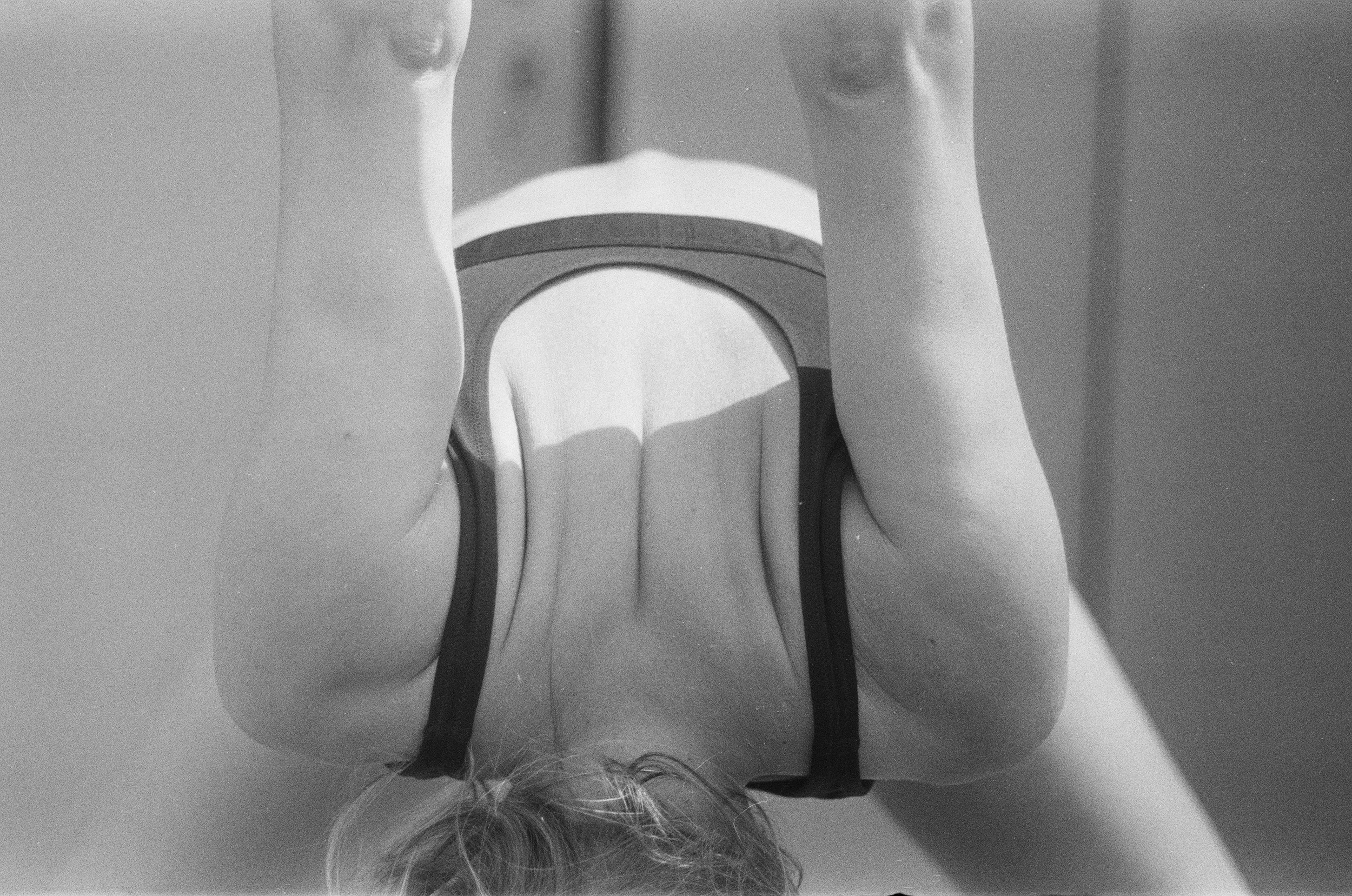 Back view of a person with short hair wearing a sports bra and shorts, standing indoors.