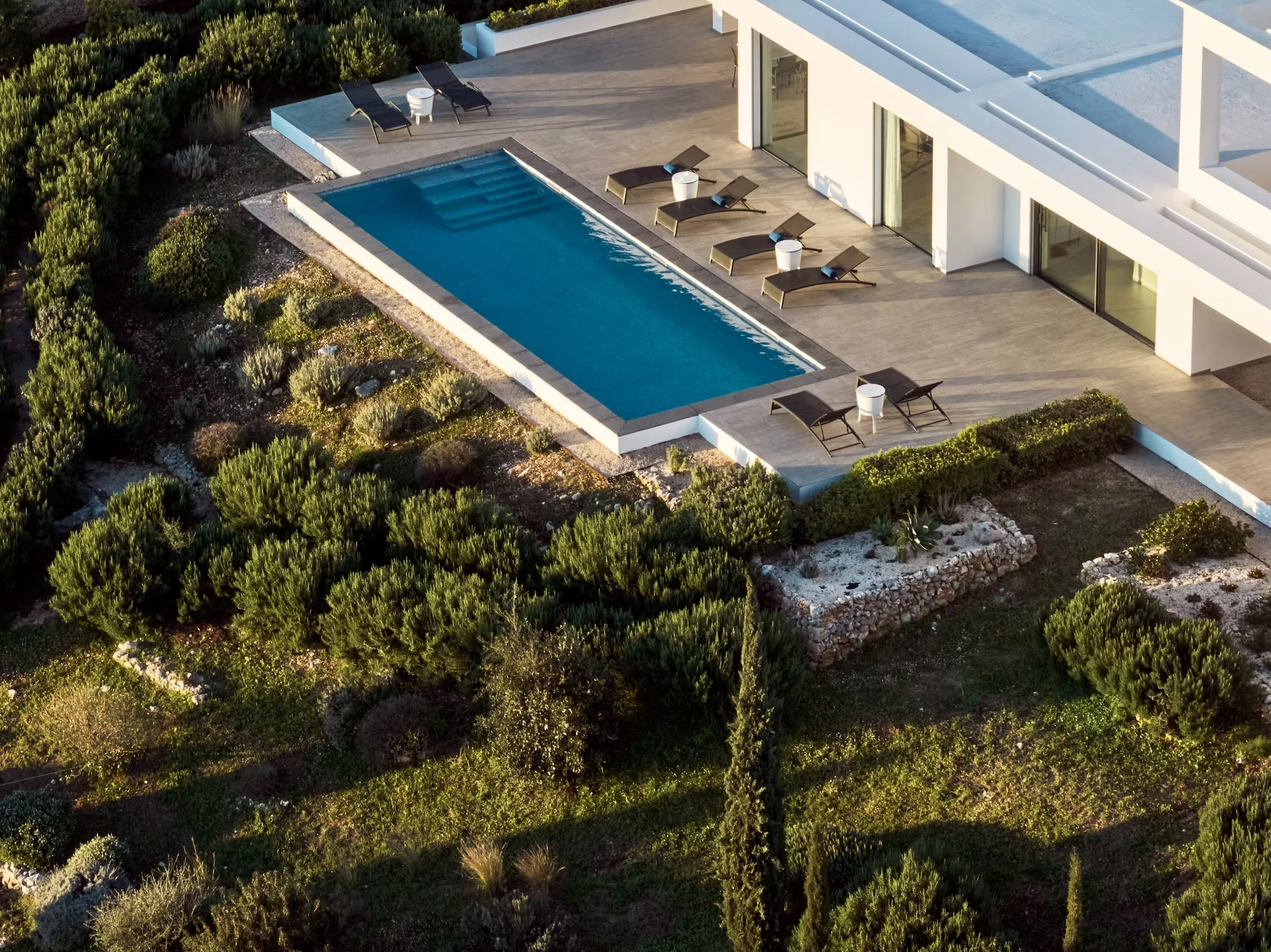 Aerial view of a modern house with a swimming pool, surrounded by greenery and landscaped garden.