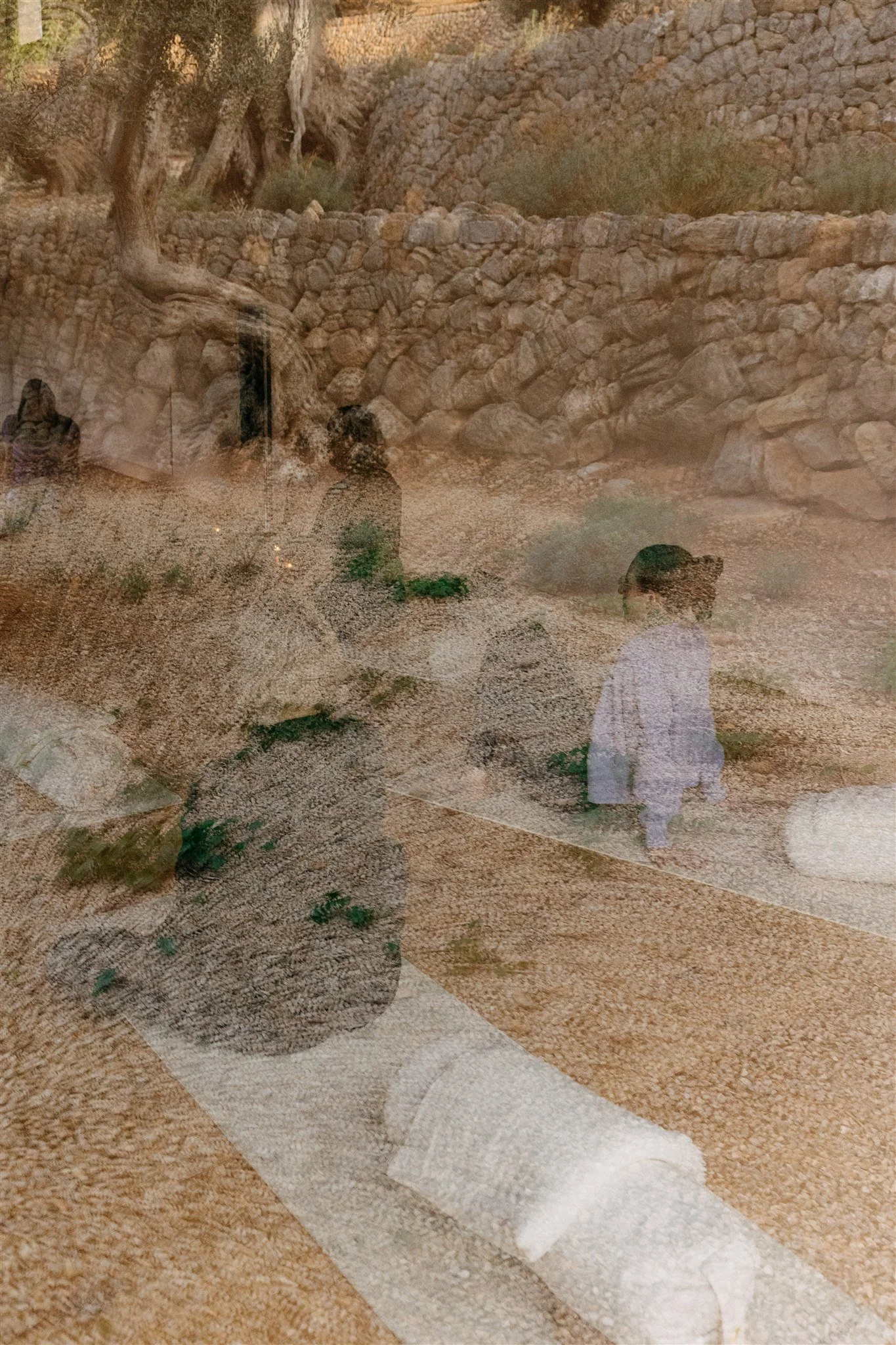 Reflection of people, trees, and rocky terrain in a glass window or mirror.