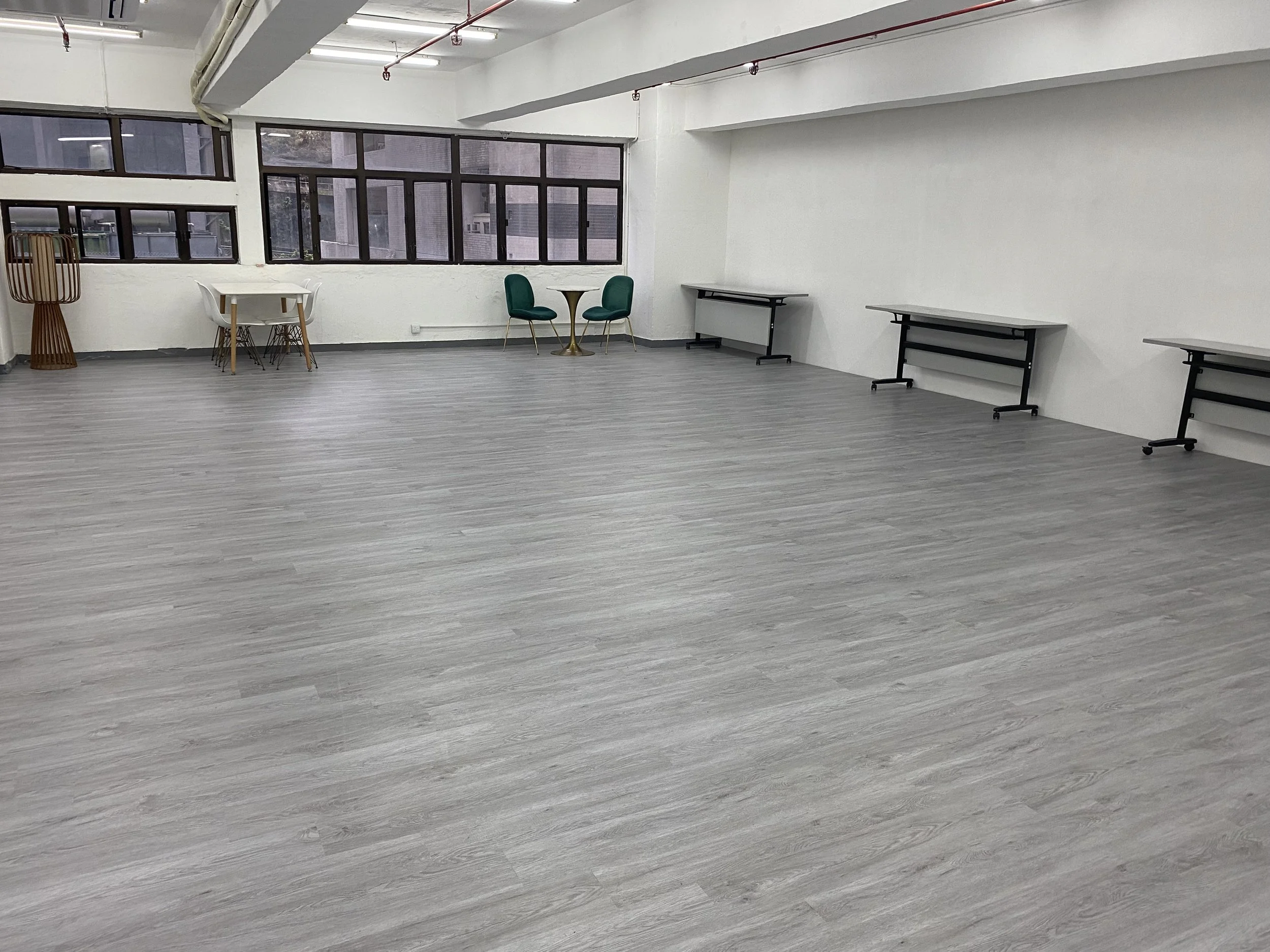 A flexible workshop space layout showing folded seminar tables pushed against the wall, demonstrating the highly adaptable open floor plan.