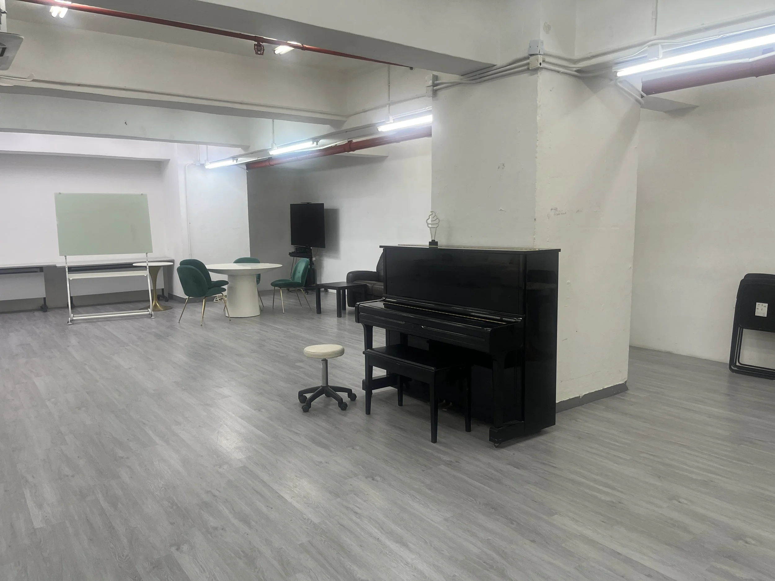 A black upright piano sitting in the modern spacious Room 1 layout at The Hang Event Space.