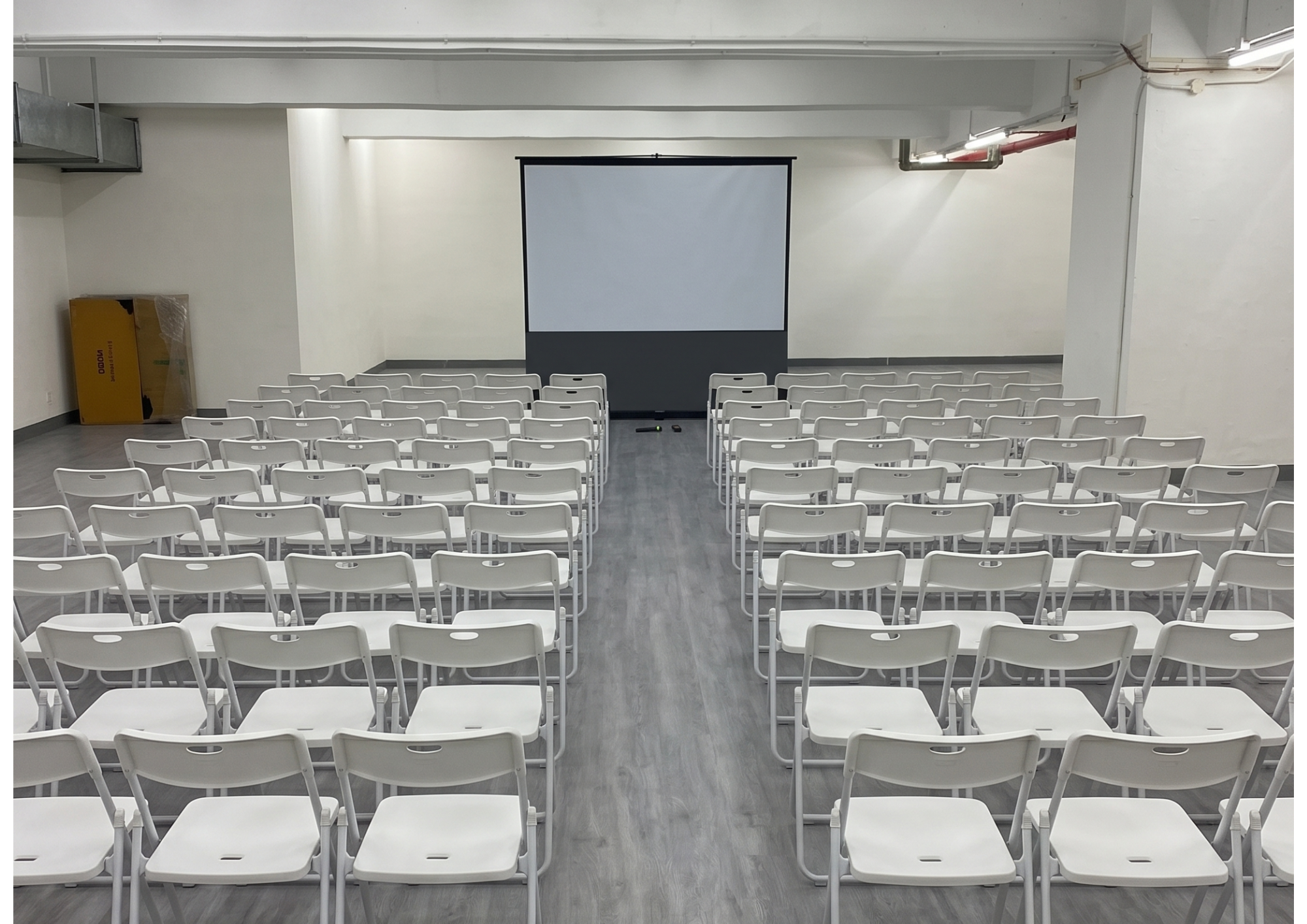 A corporate conference layout with rows of seminar chairs facing a presentation screen inside a professional business event space.