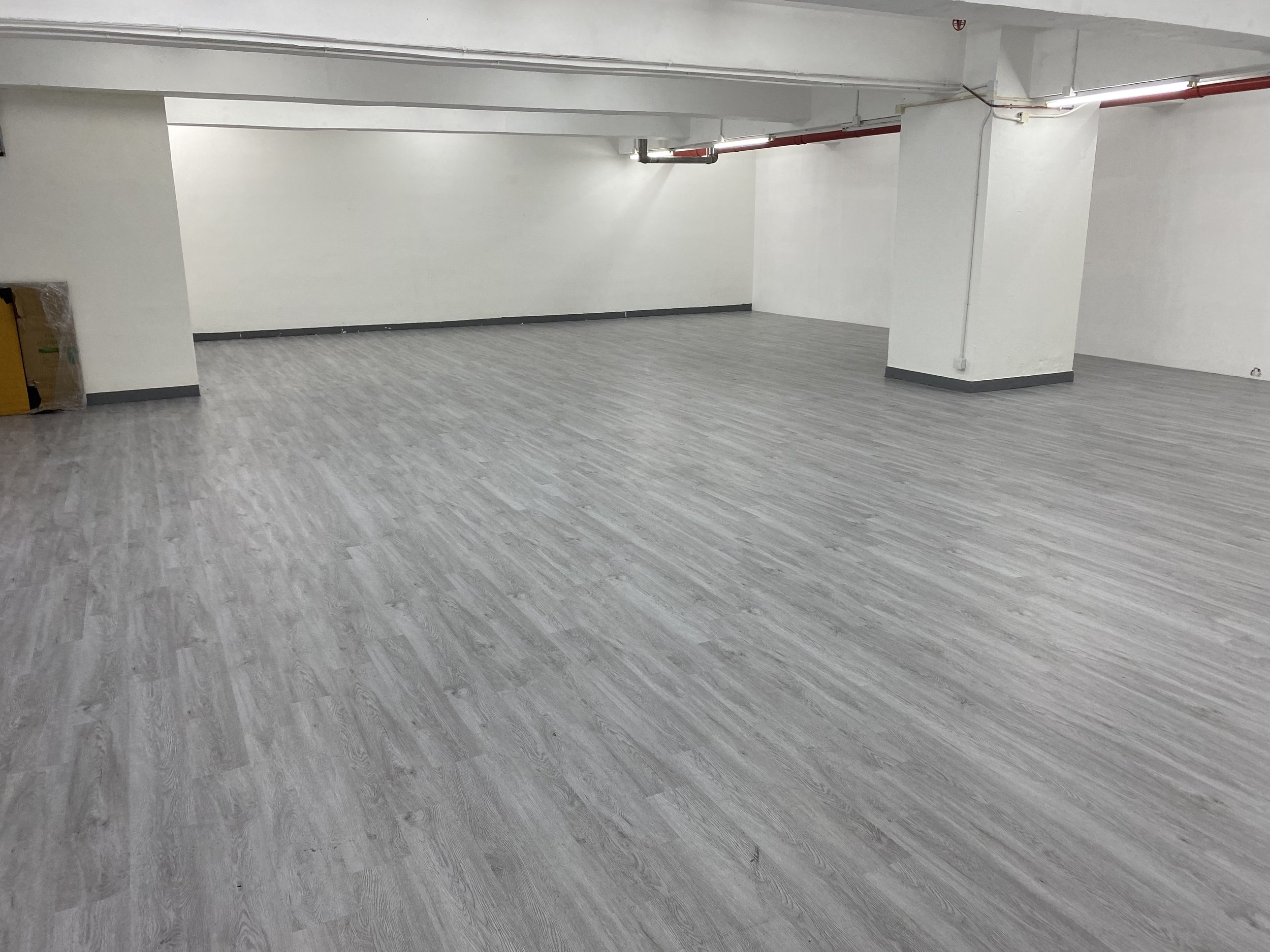 An empty clean room layout with white pillars and walls, ideal for temporary art exhibitions or yoga studio rental in Hong Kong.