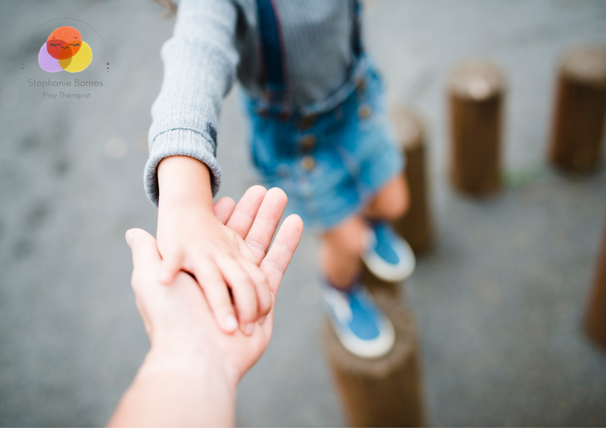 A child holding an adult's hand while walking outdoors.