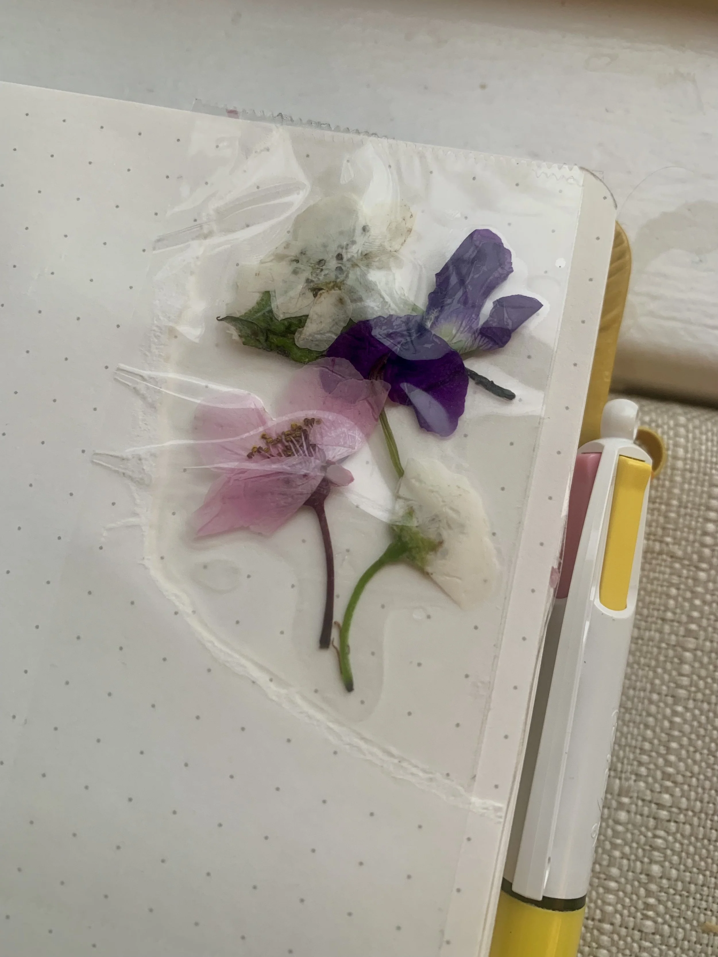 Ripped bullet journal paper with pressed flowers in the area.