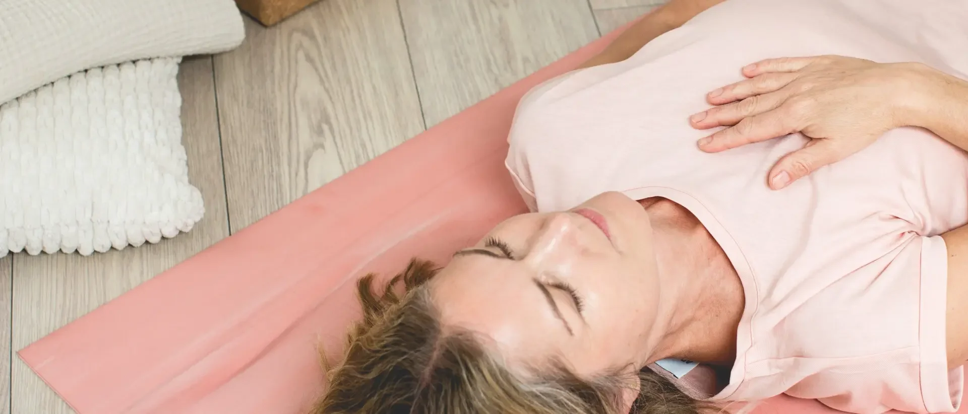 Eine ältere Frau liegt entspannt auf dem Boden, die Hand auf der Brust, und scheint sich auszuruhen.