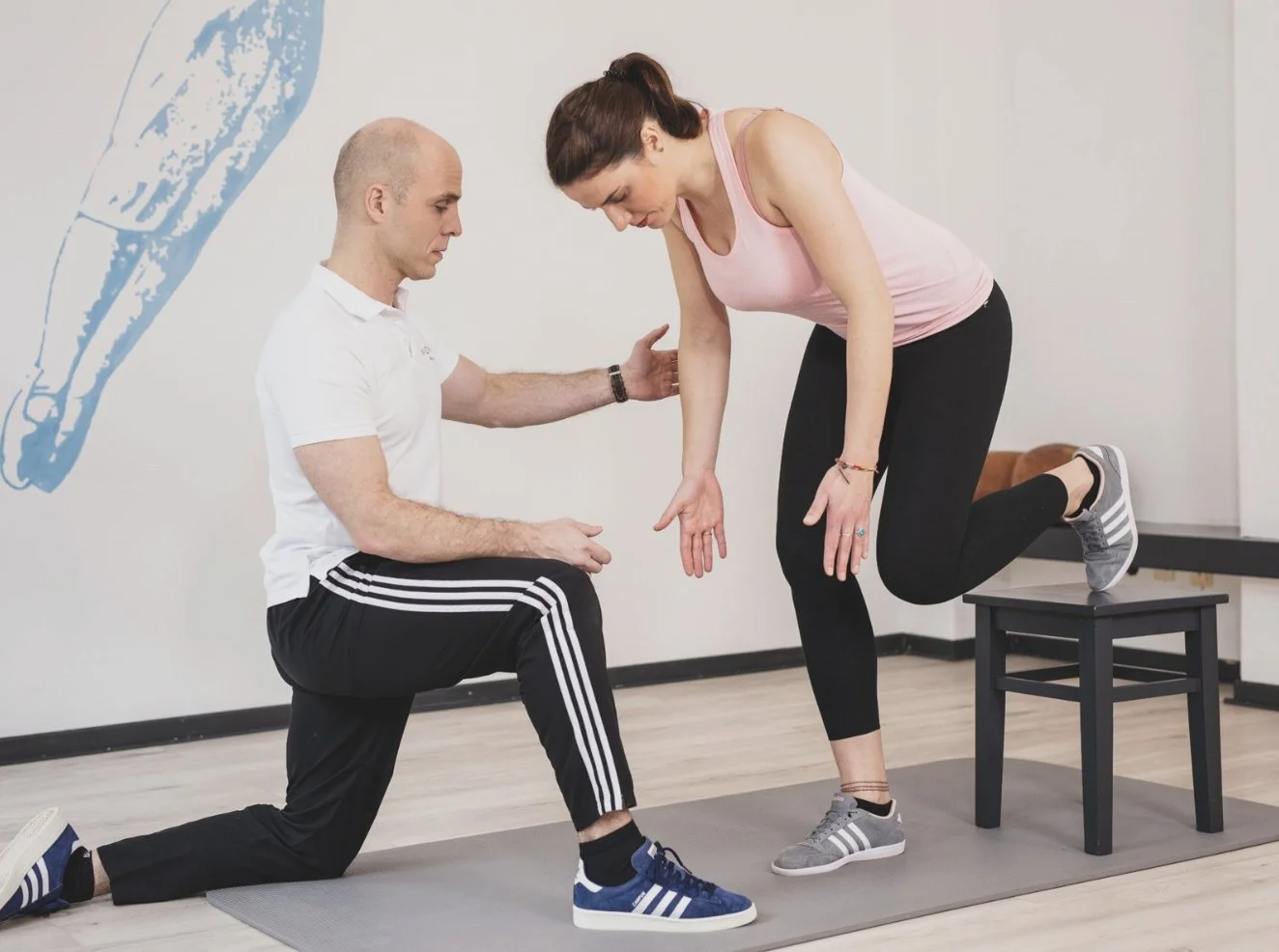 Ein Trainer hilft einer Frau bei Ausfallschritten in einem Fitnessstudio.