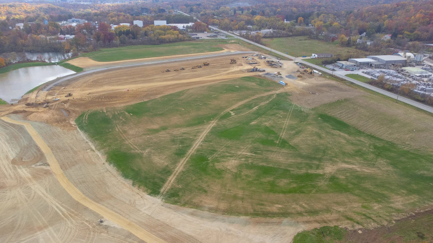 Aerial view of a construction site with multiple bulldozers and earth-moving equipment on a large area of cleared land.