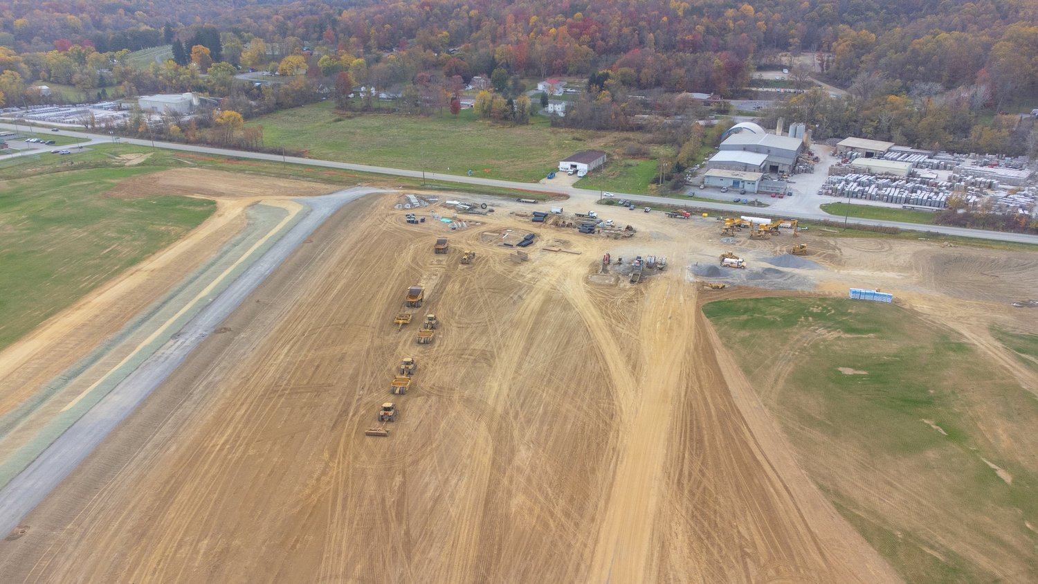 Aerial view of a construction site with heavy machinery, dirt roads, and cleared land.