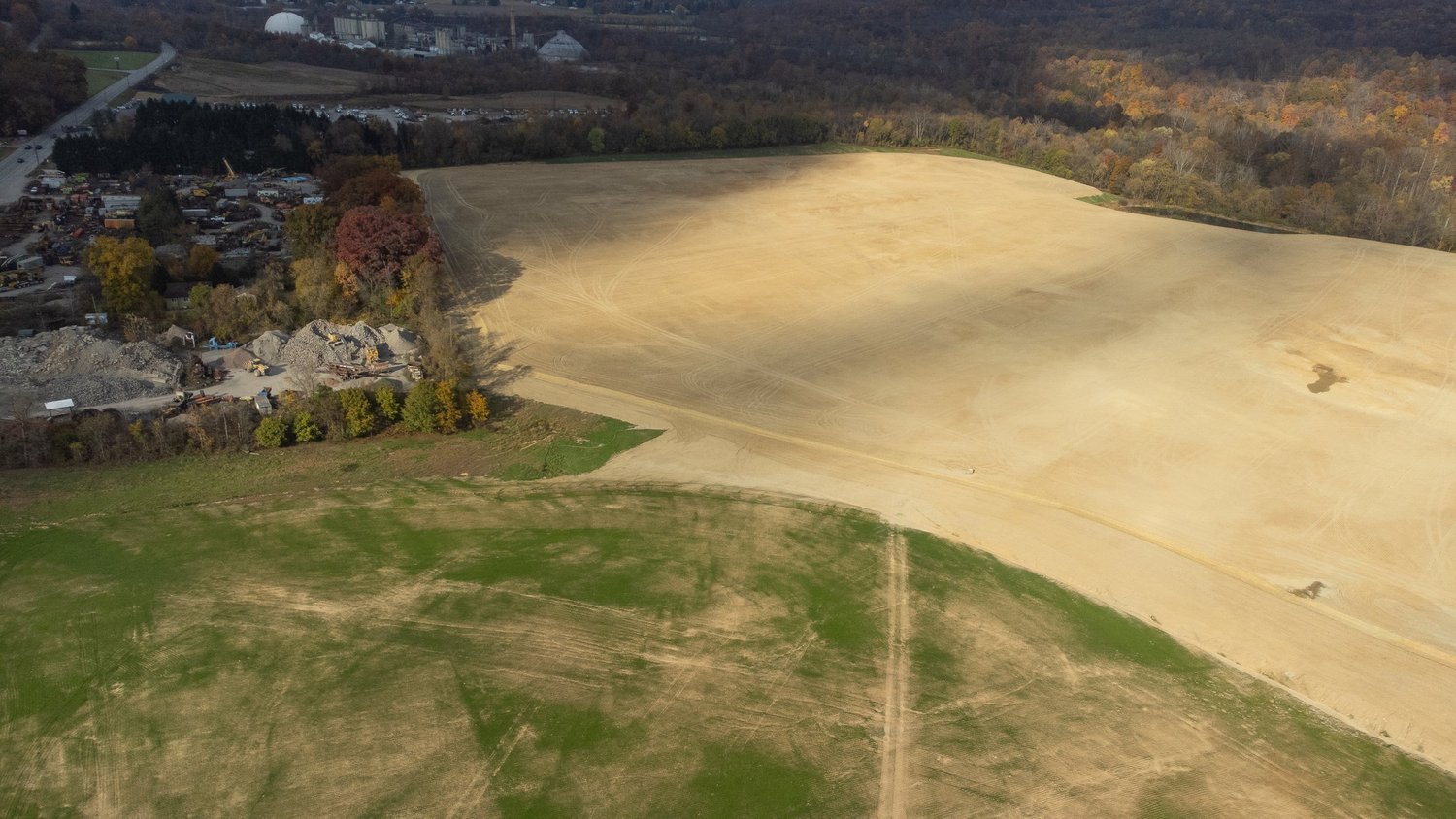An aerial view of a construction site with cleared land and construction equipment.