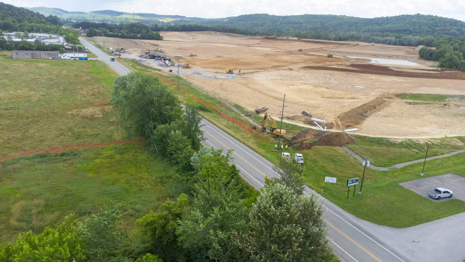 A construction site with heavy machinery working on land and a road running through the area.