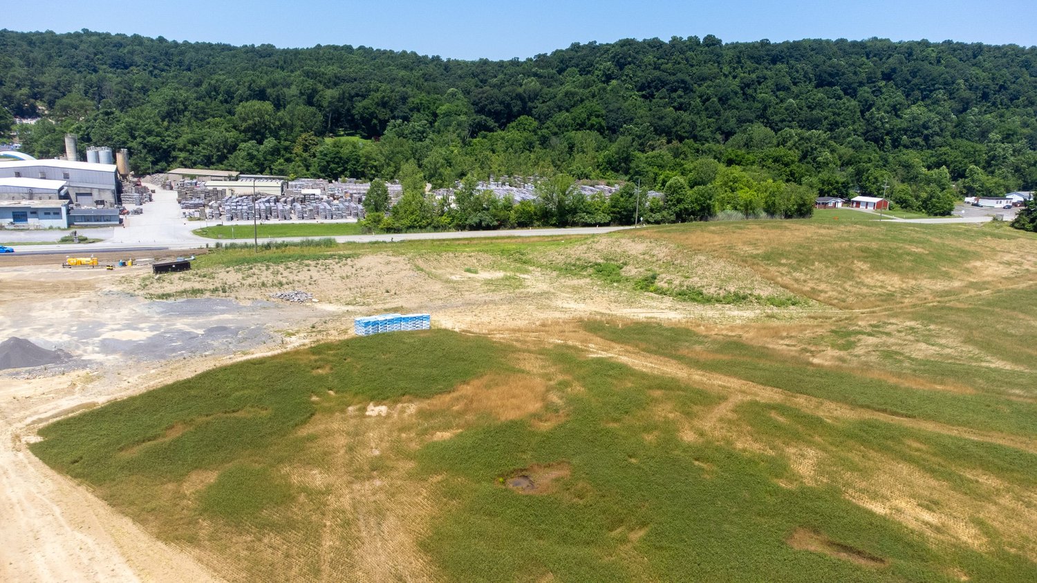 Aerial view of a construction site with patches of green grass and brown dirt in the foreground.