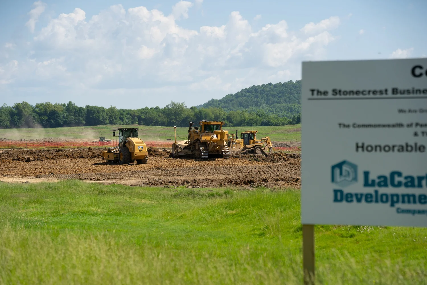 Bulldozers grading land at Stonecrest Business Park behind the project sign.