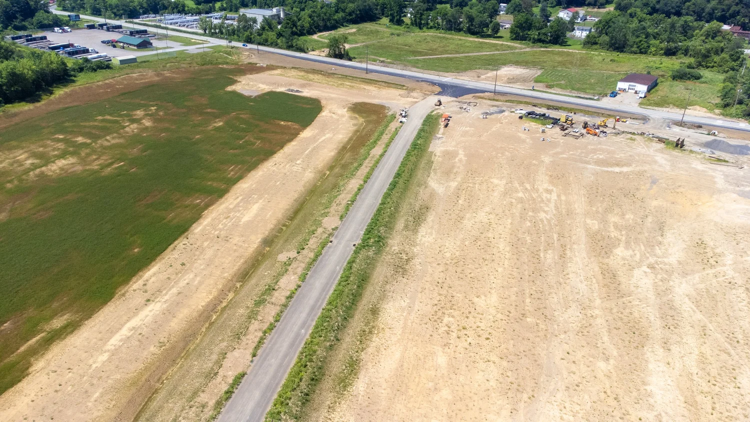 Aerial view of a construction site with dirt and grass patches, a small road being built.