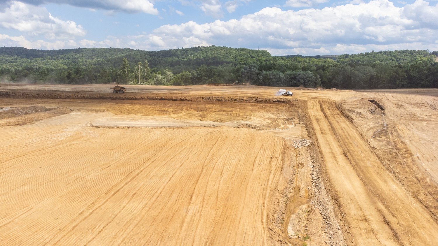 Construction site with large excavated area, heavy machinery working on the dirt.