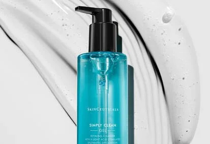 Blue skincare bottle labeled 'Simply Clean Gel' from SkinCuticals on a white surface with water droplets.