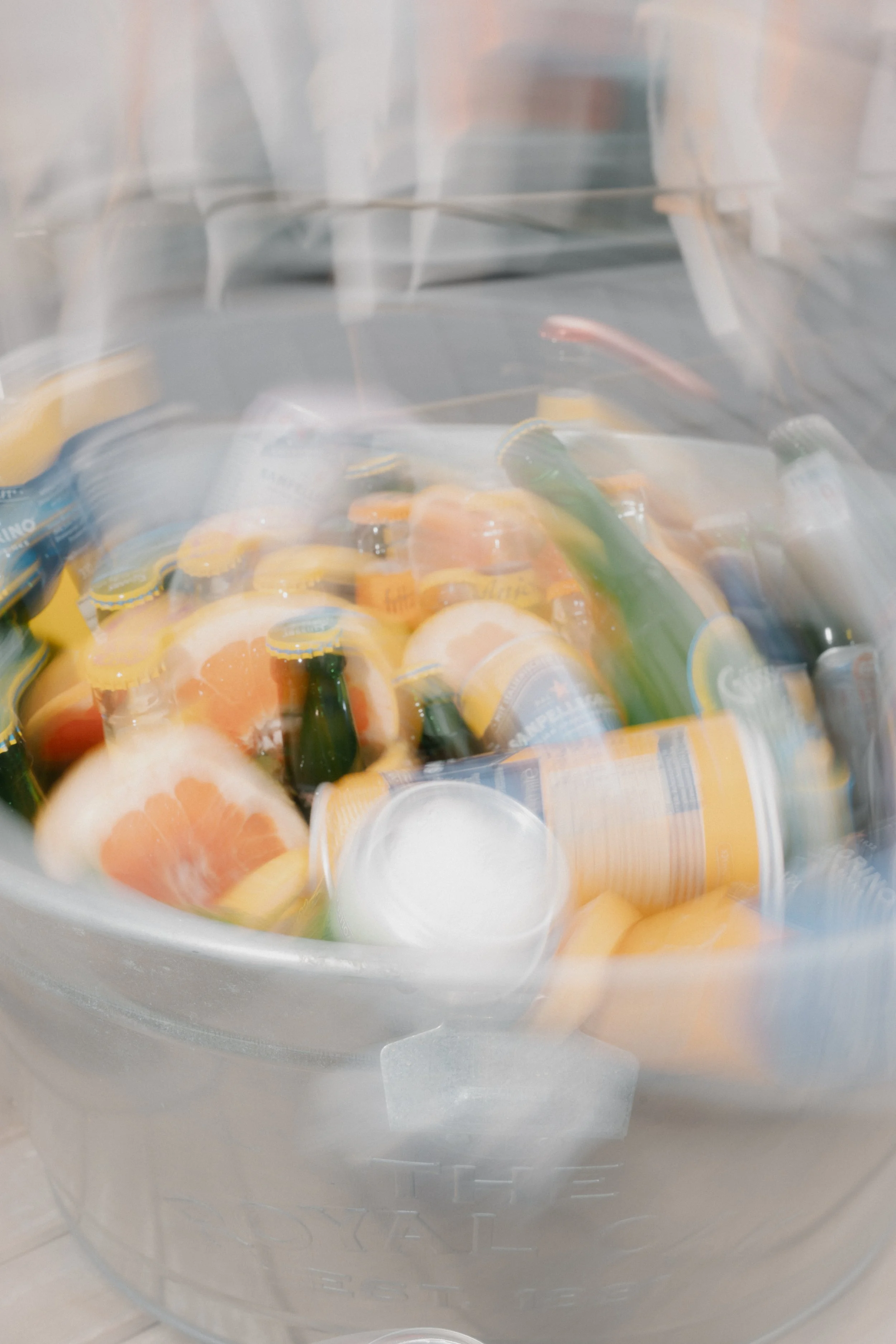 Eimer mit Getränkekisten, Flaschen und Früchten, sichtbar durch eine bewegte, verschwommene Folie