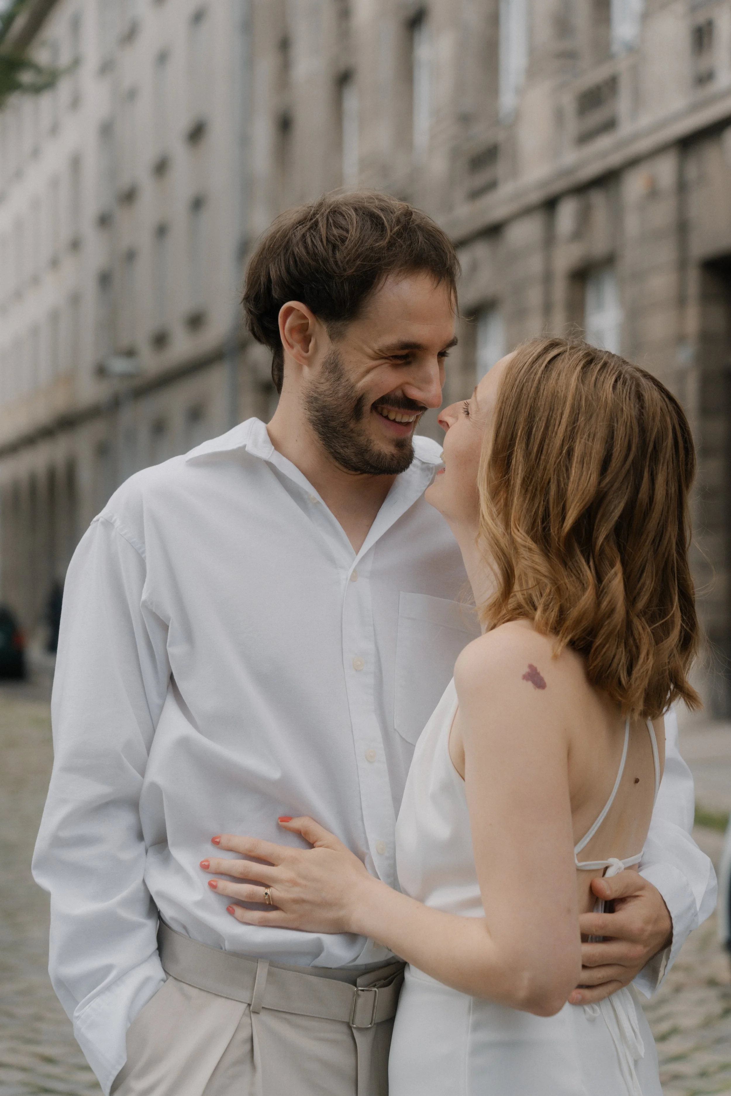 Ein lachendes Paar beim Spazieren in der Stadt, die Frau hat ein Tattoo auf der Schulter.