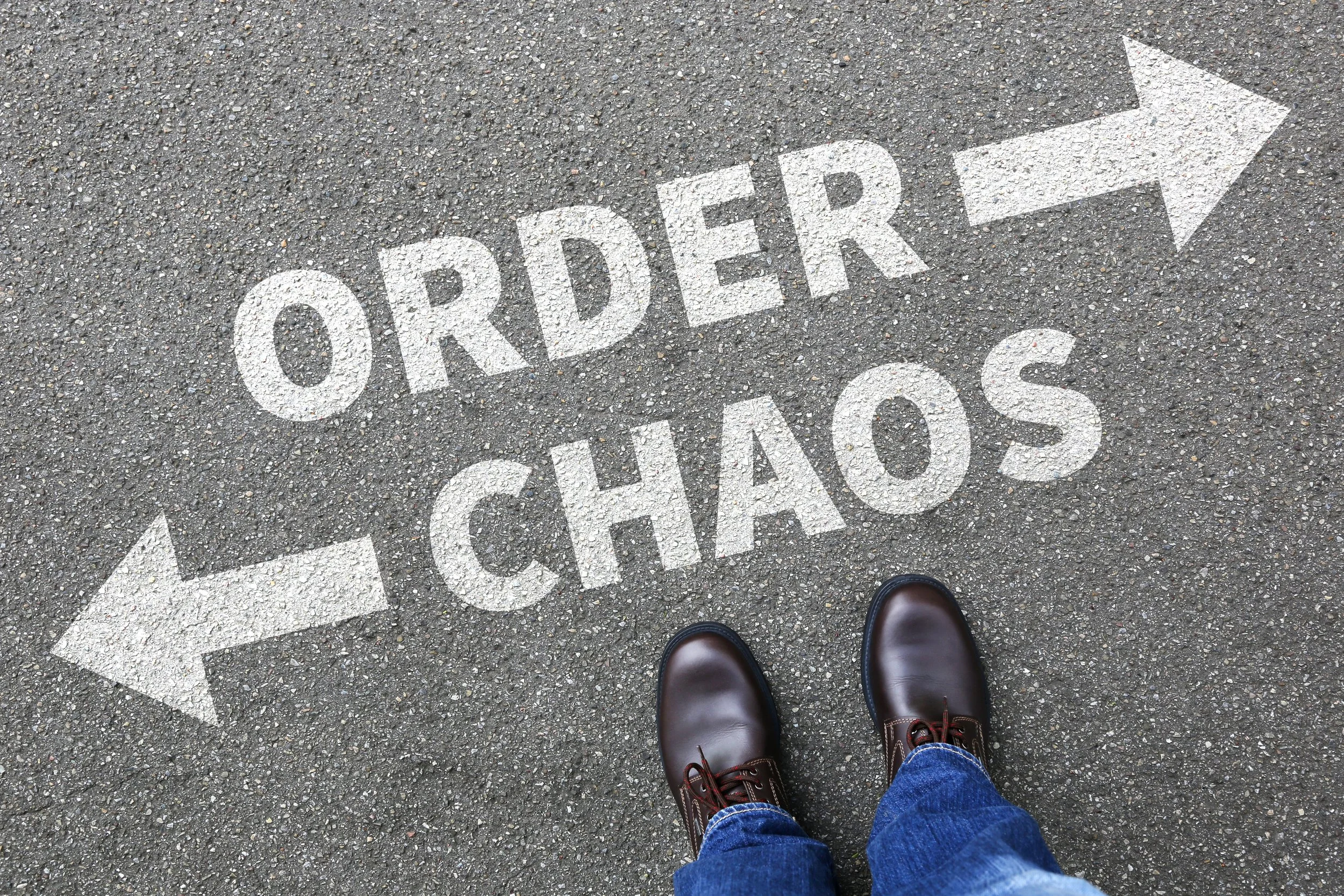 Image shows a street with the words ORDER and CHAOS, an arrow pointing in different directions after each word, and boots standing in front of the words.