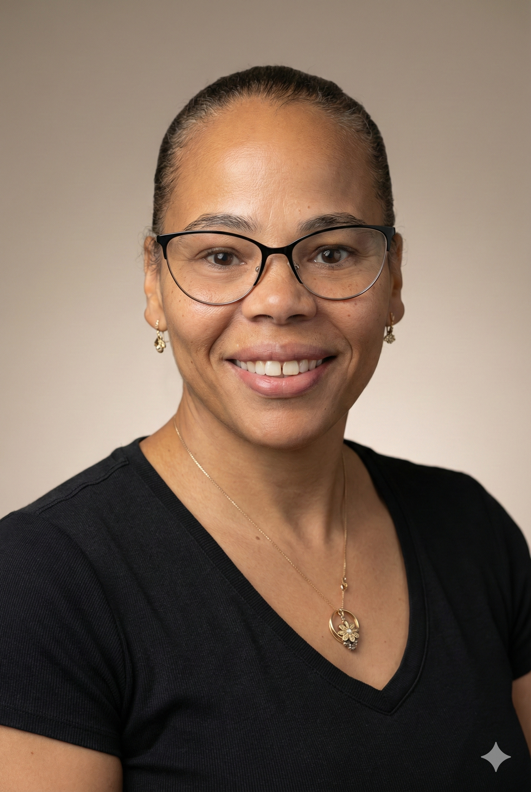 Headshot of a woman with glasses, earrings, and a necklace, smiling at the camera against a plain background.