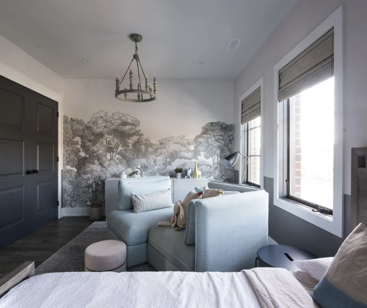 Modern bedroom with light blue sectional sofa, forest mural, chandelier, and large windows.