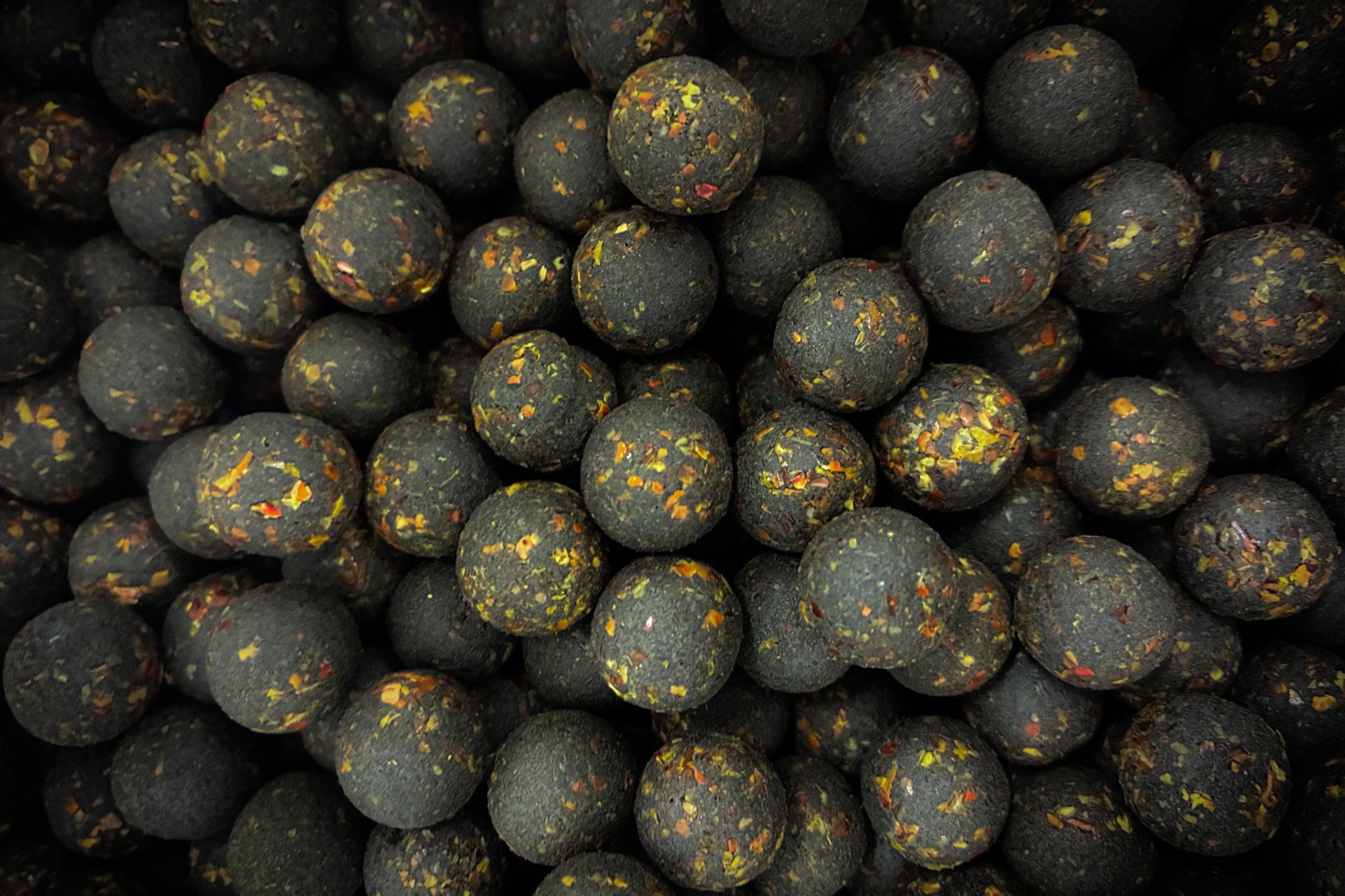 Close-up of black peppercorns with colorful flecks on their surface