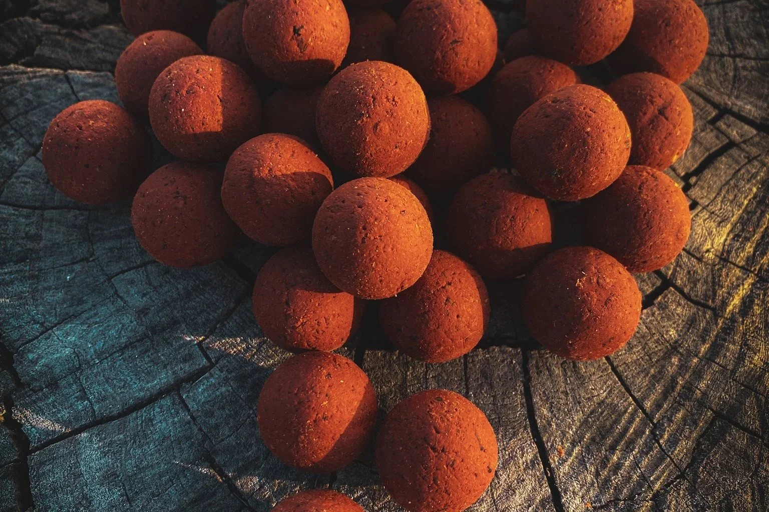 Group of reddish-brown clay balls on a cracked wooden surface.