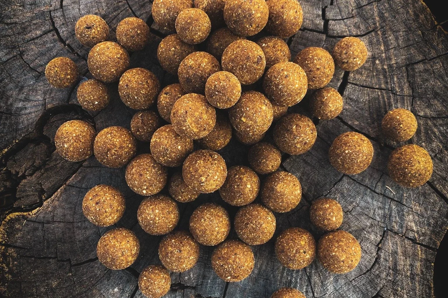 A group of brown, round, textured balls sitting on a weathered wooden surface with visible cracks.