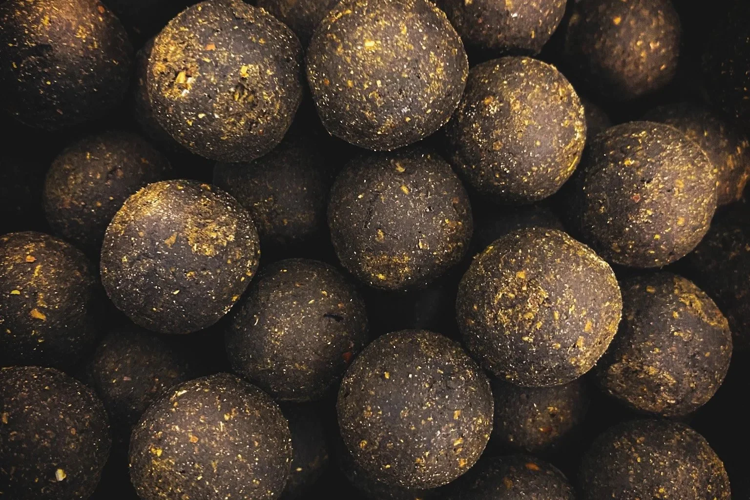 Close-up of black, round energy balls with gold flecks.