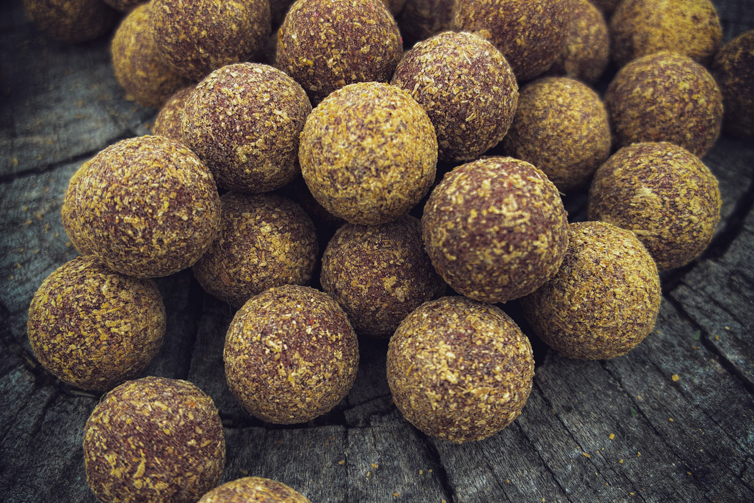 Group of round herbal energy balls with a textured surface on a rustic wooden surface.