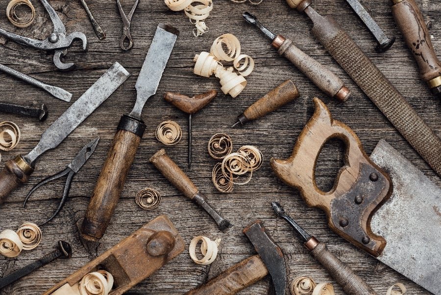 Picture of woodworking hand tools including saws, chisels, planes, pliers, and curly wood shavings.
