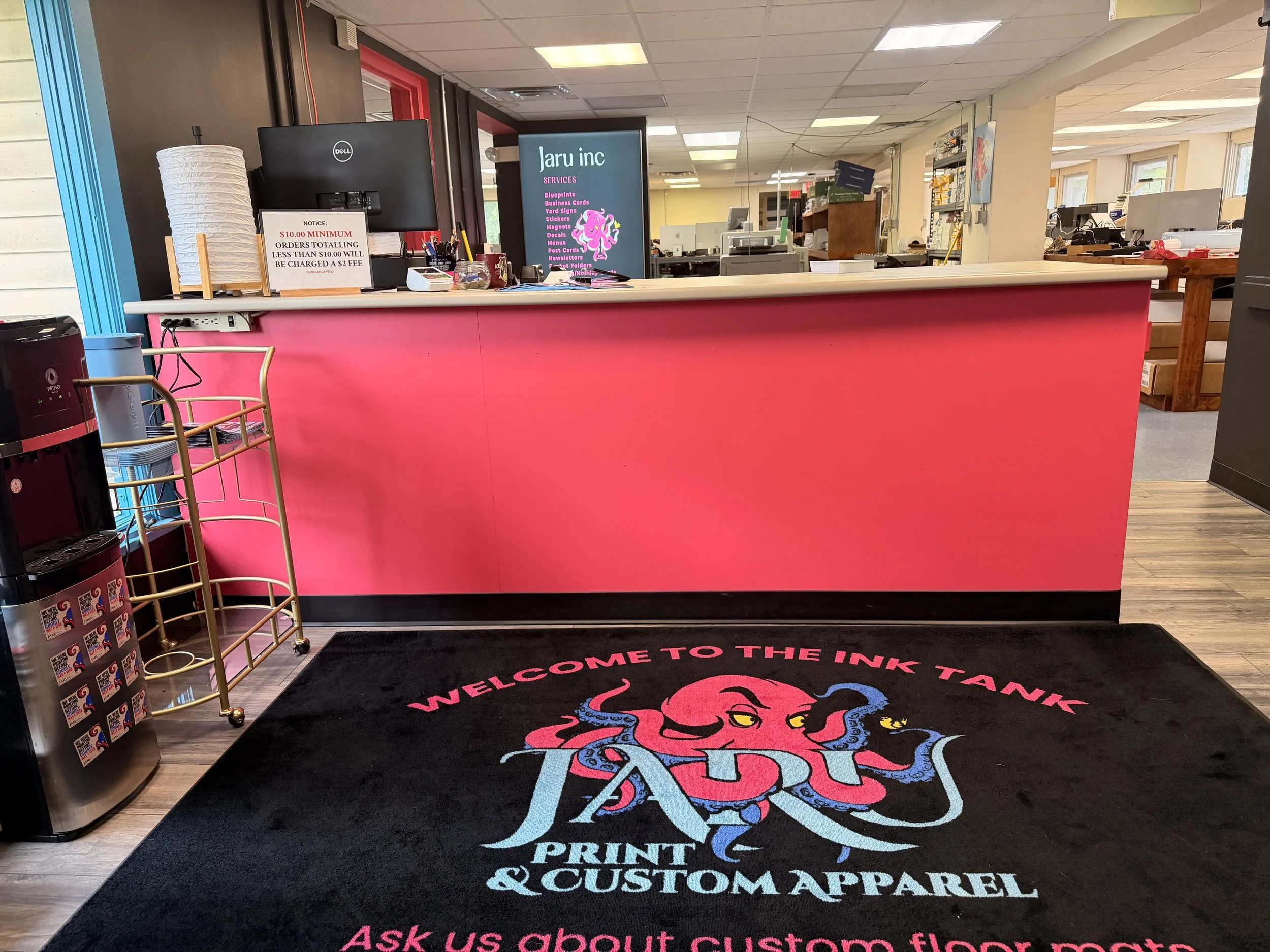 Front counter and custom floor mat at Jaru Print and Custom Apparel, a State College, PA printing and sign shop