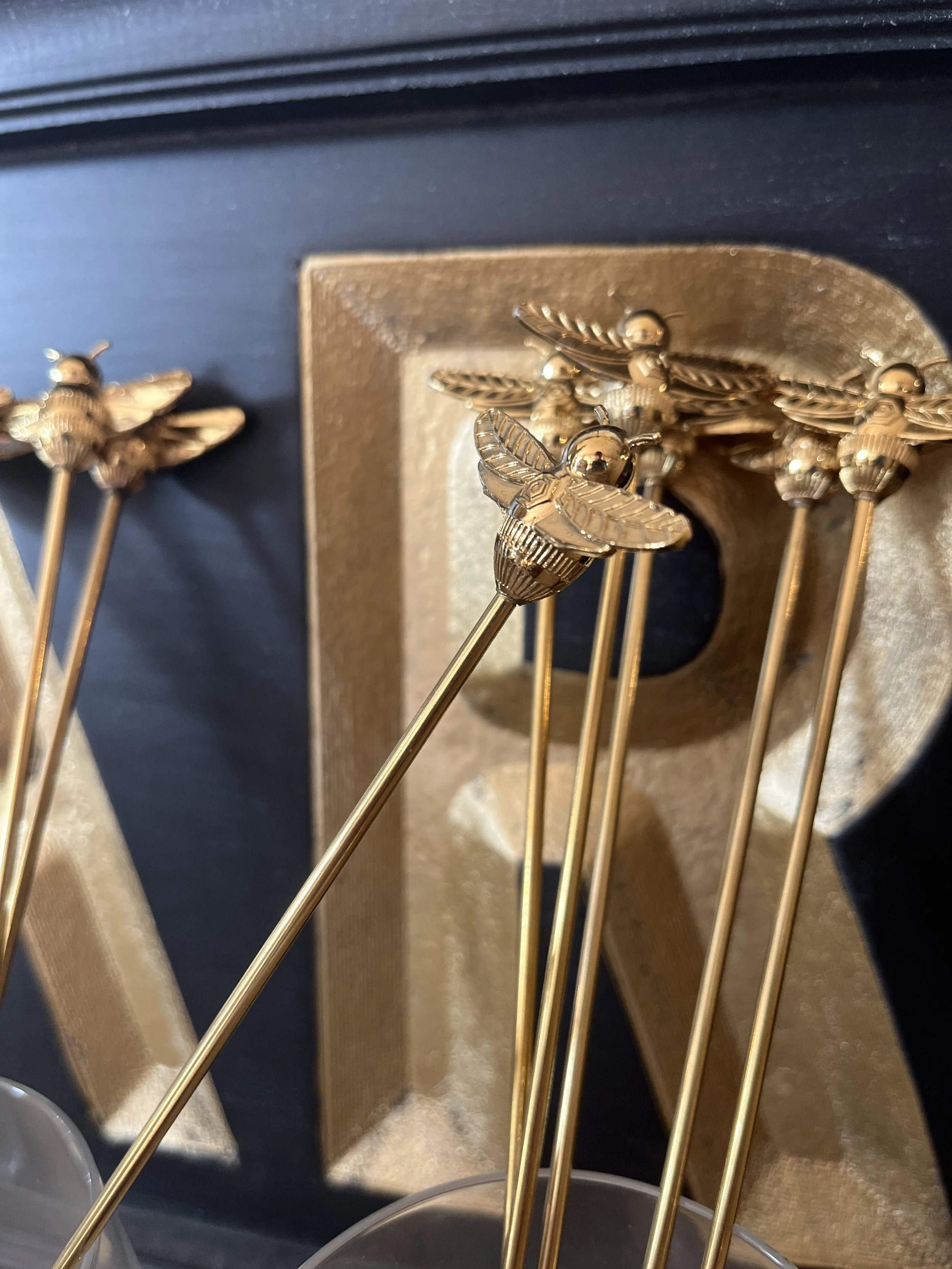 Brass Bee Stir Sticks displayed in a glass at Studio 304