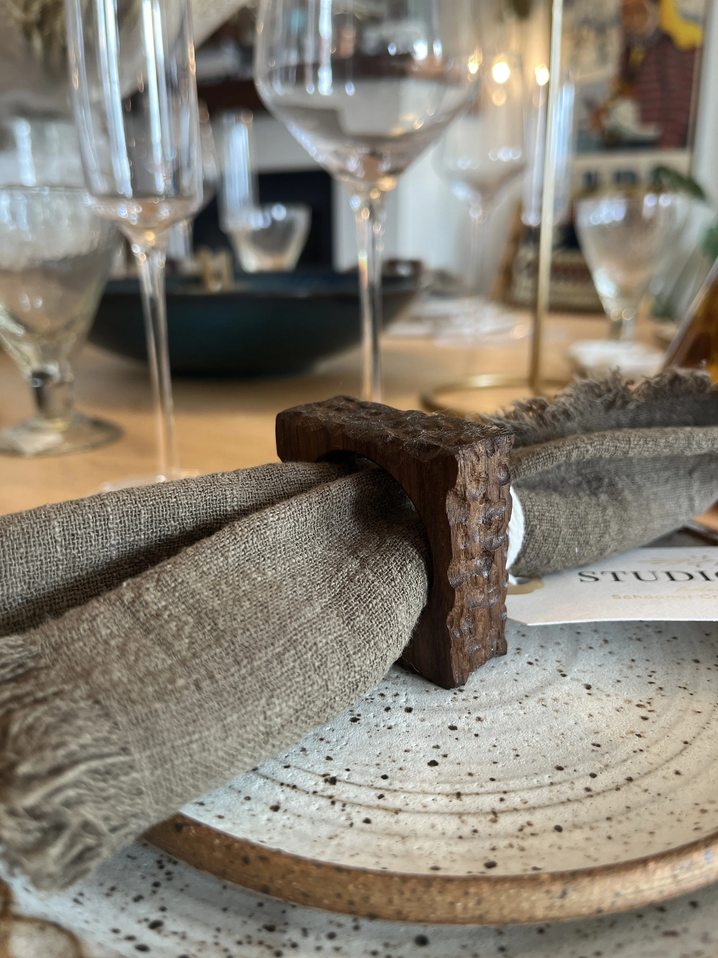 Textured finished wooden napkin ring holding a white linen napkin on a dining room table designed by Schooner Creek Designs