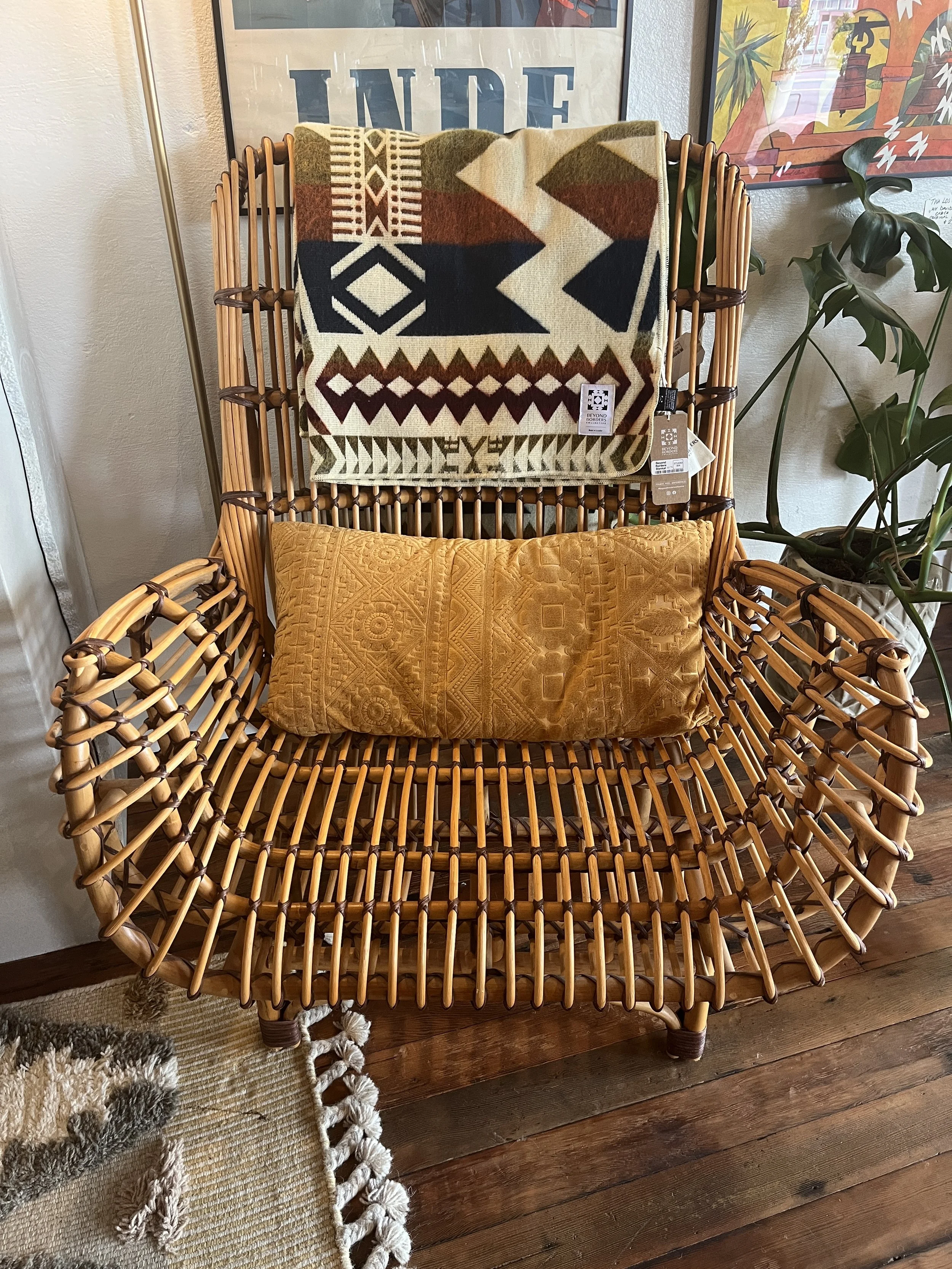 Wicker Armchair by a plant with vintage posters in the background