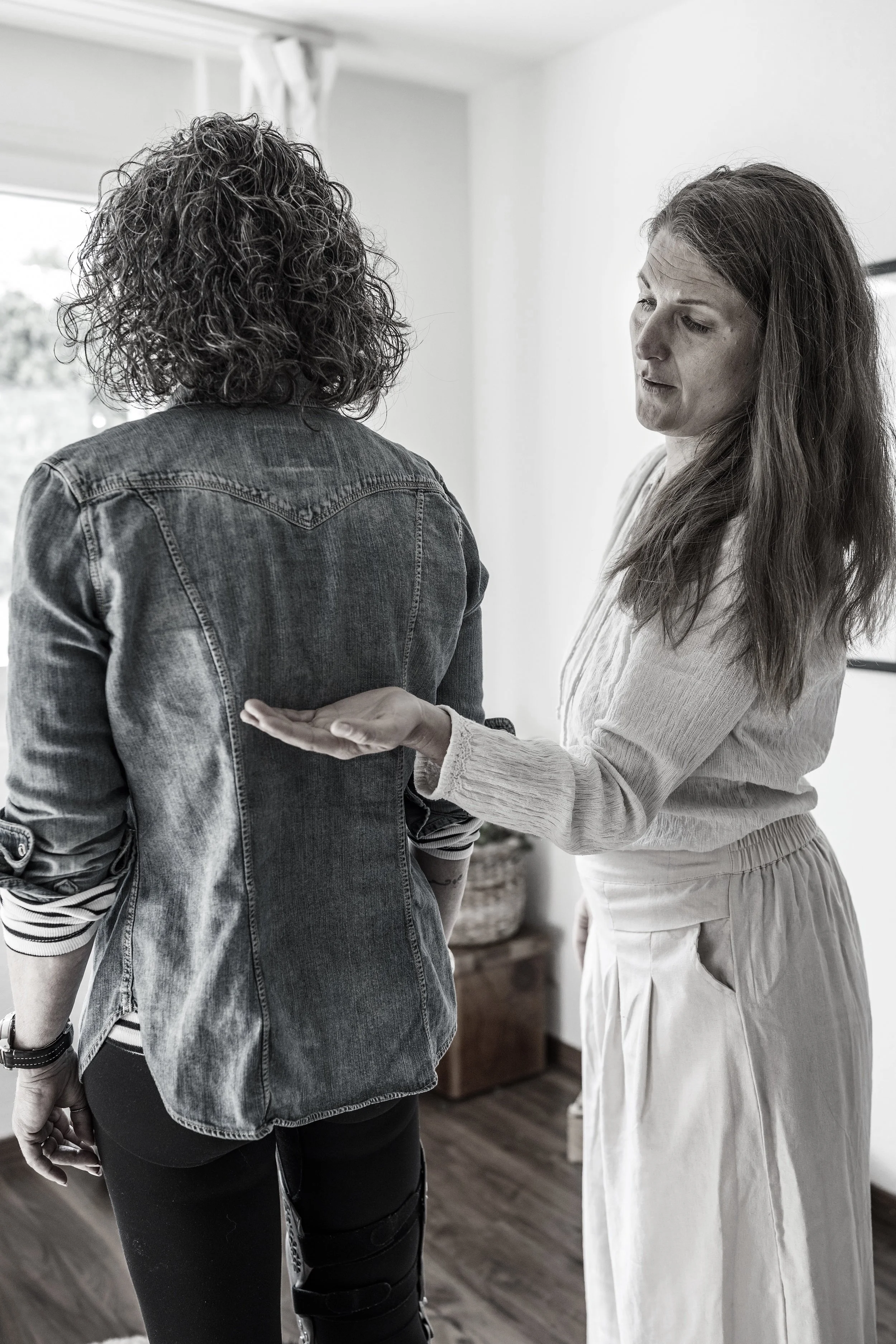 Zwei Frauen unterhalten sich in einem Raum, eine zeigt mit der Hand auf die andere, die andere schaut besorgt.