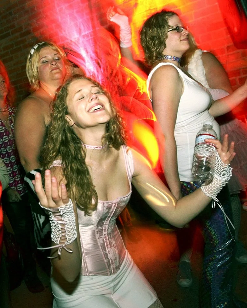 A young woman in a club dressed in a pink corset, completely lost in a musical moment.