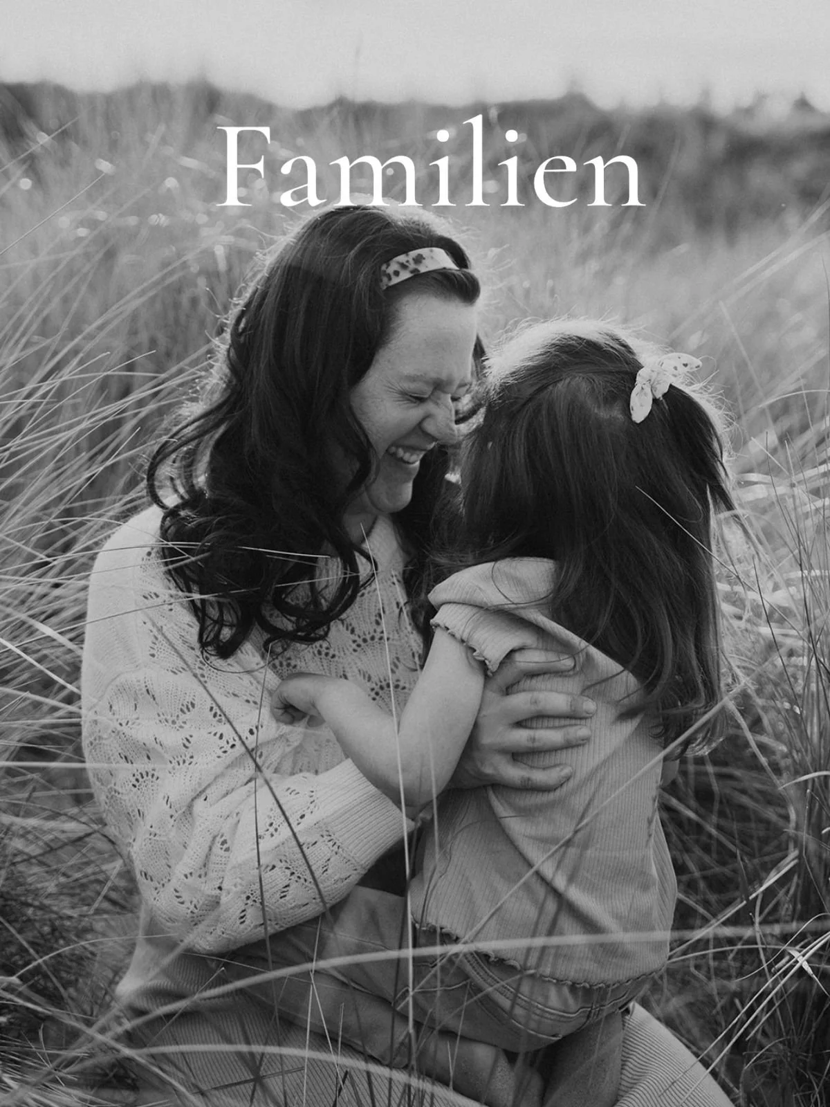 Schwarz-weiß-Foto einer lachenden Frau, die ein Kind in einem Feld umarmt.