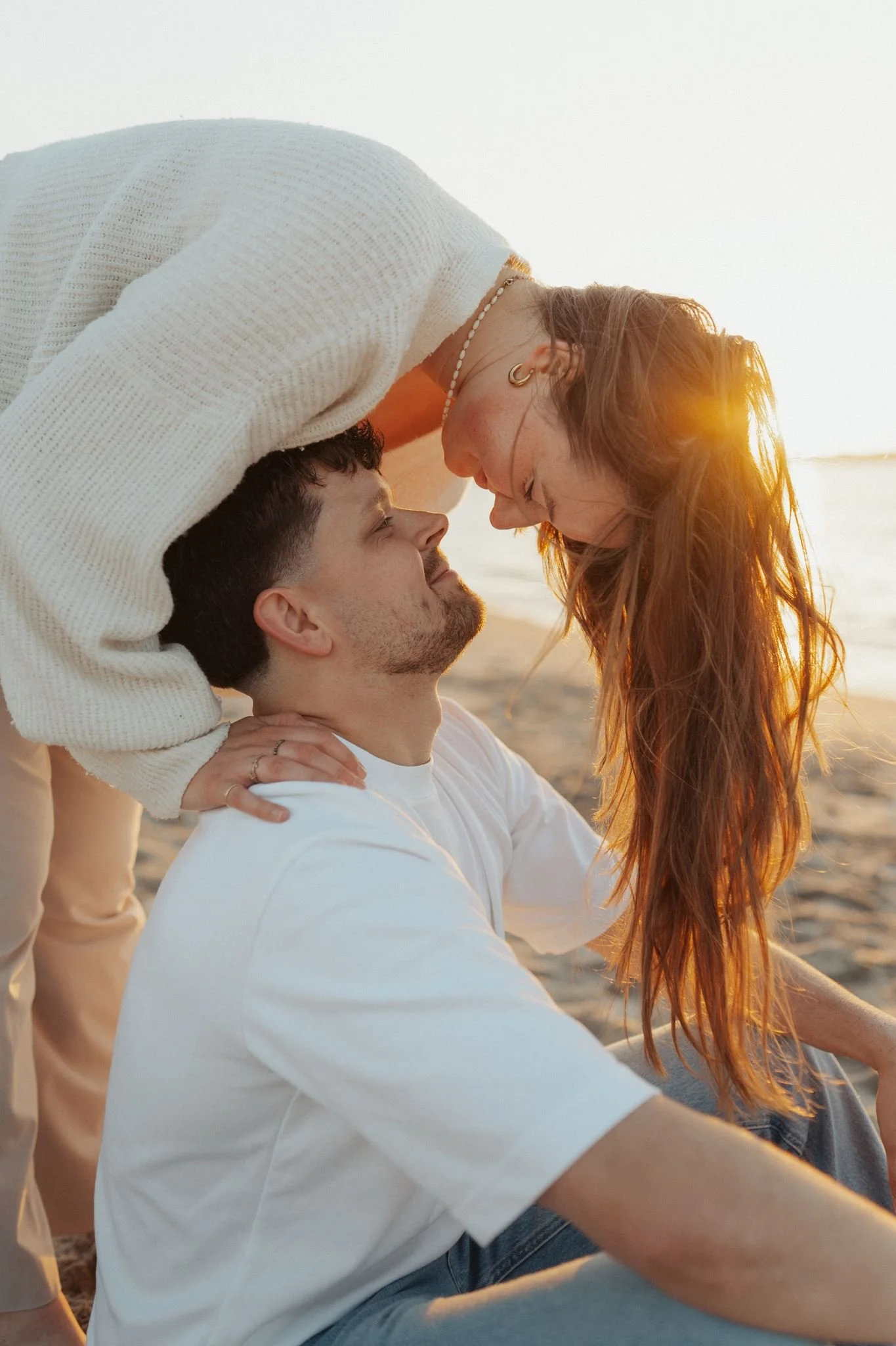 Ein Paar beim Beach-Shooting im Sonnenuntergang, das sich liebevoll berührt.
