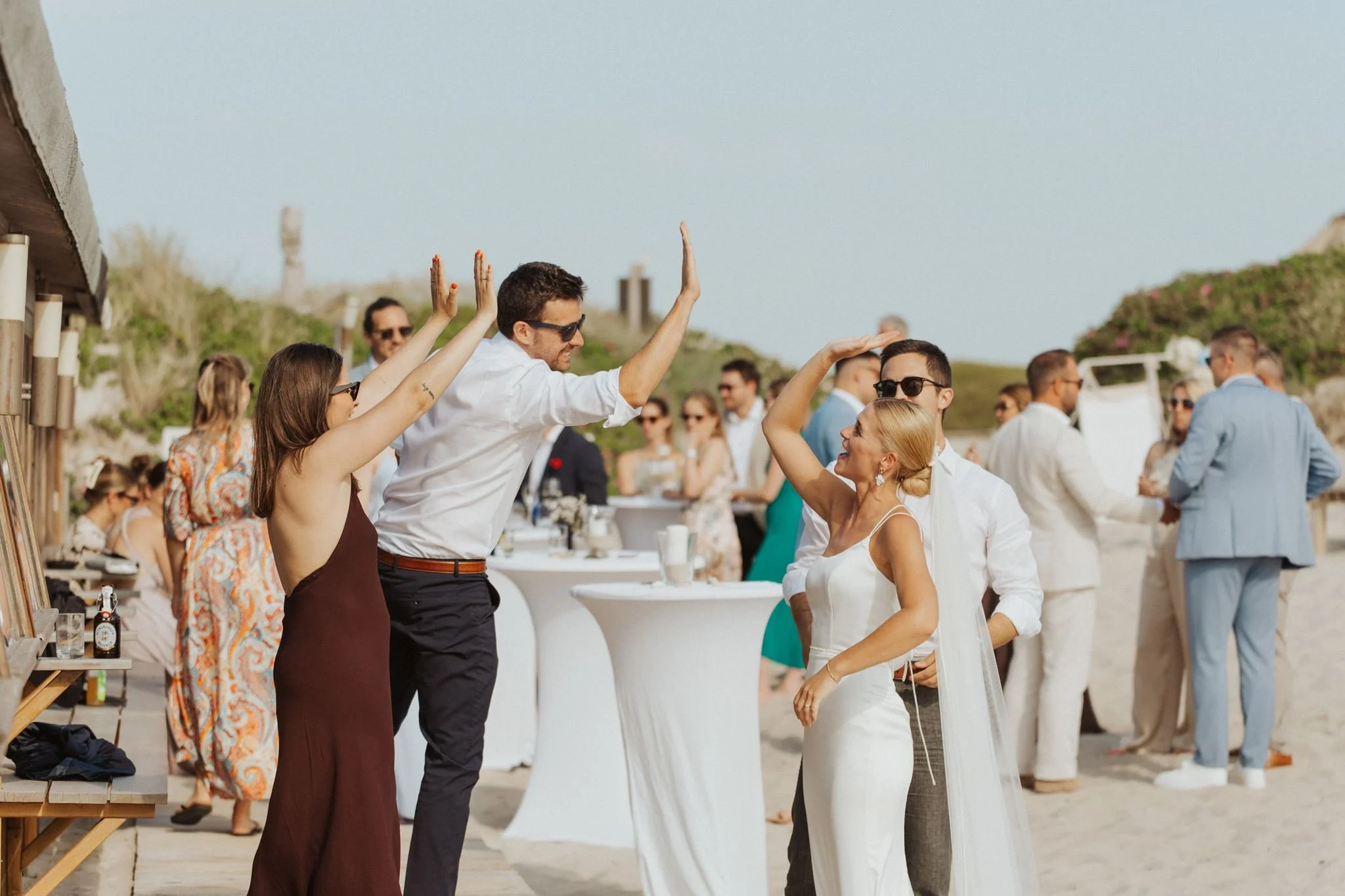 Menschen, die bei einer Strandhochzeit gemeinsam mit der Braut Einklatschen nachdem sie bei Vikingerschach gewonnen hat.